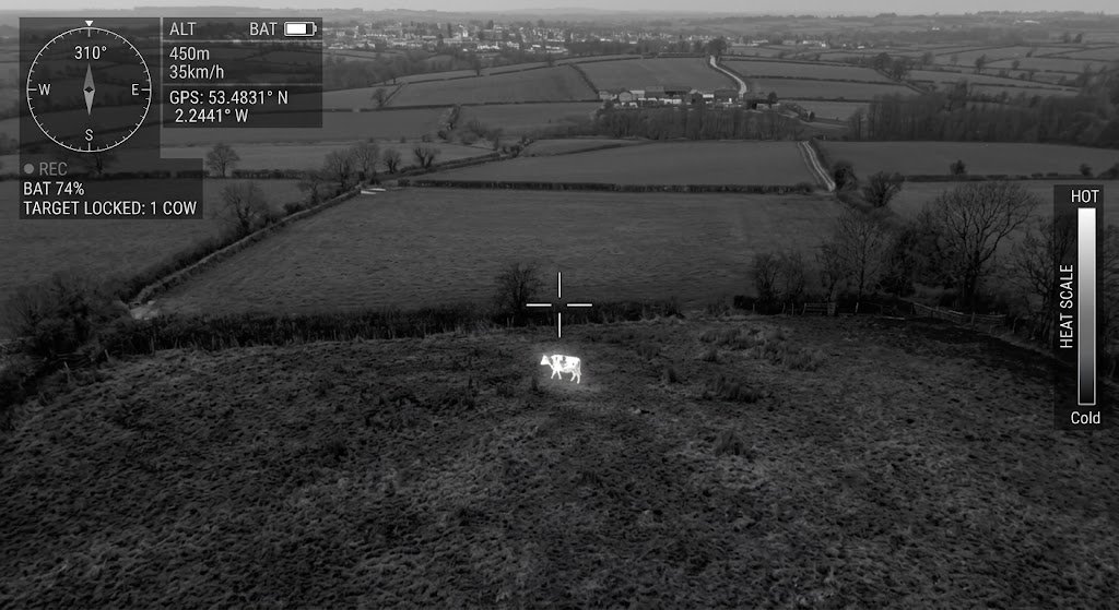 Night vision image from a drone showing a cow in a field, with overlay details including GPS location, battery level, altitude, speed, and a heat scale.