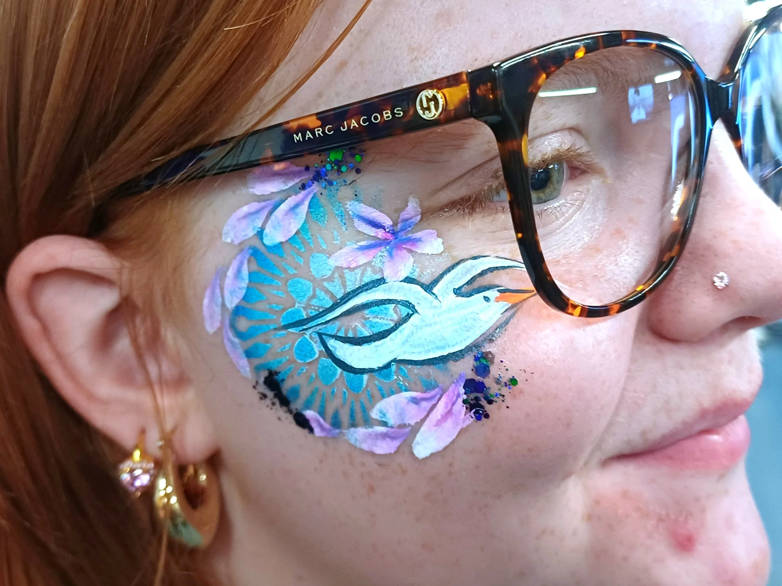 Close-up of a woman with detailed face paint featuring purple and blue flower patterns