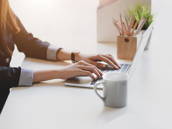 Person working on a laptop at a bright desk.