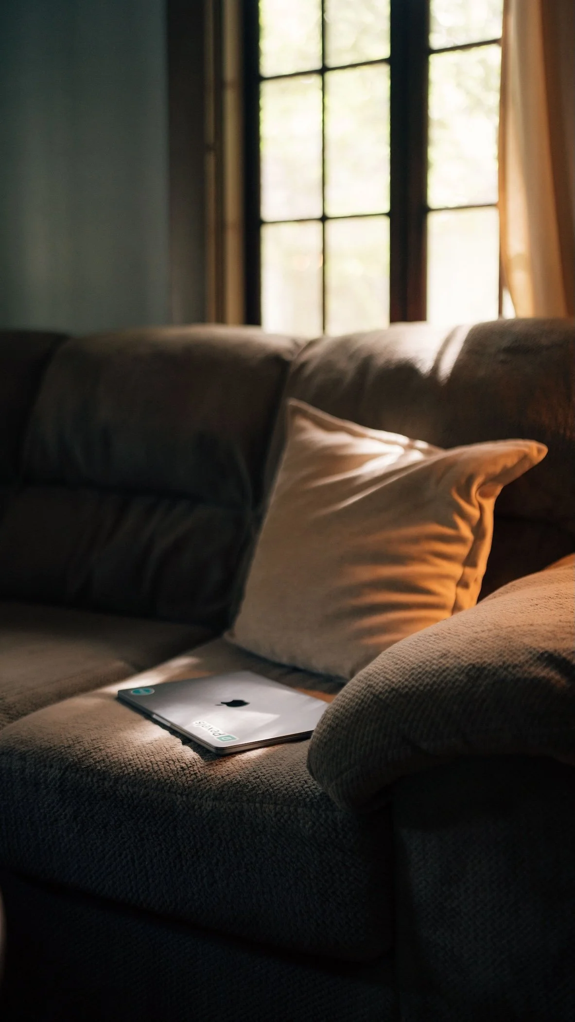 Sunlit sofa with a tablet beside the window.
