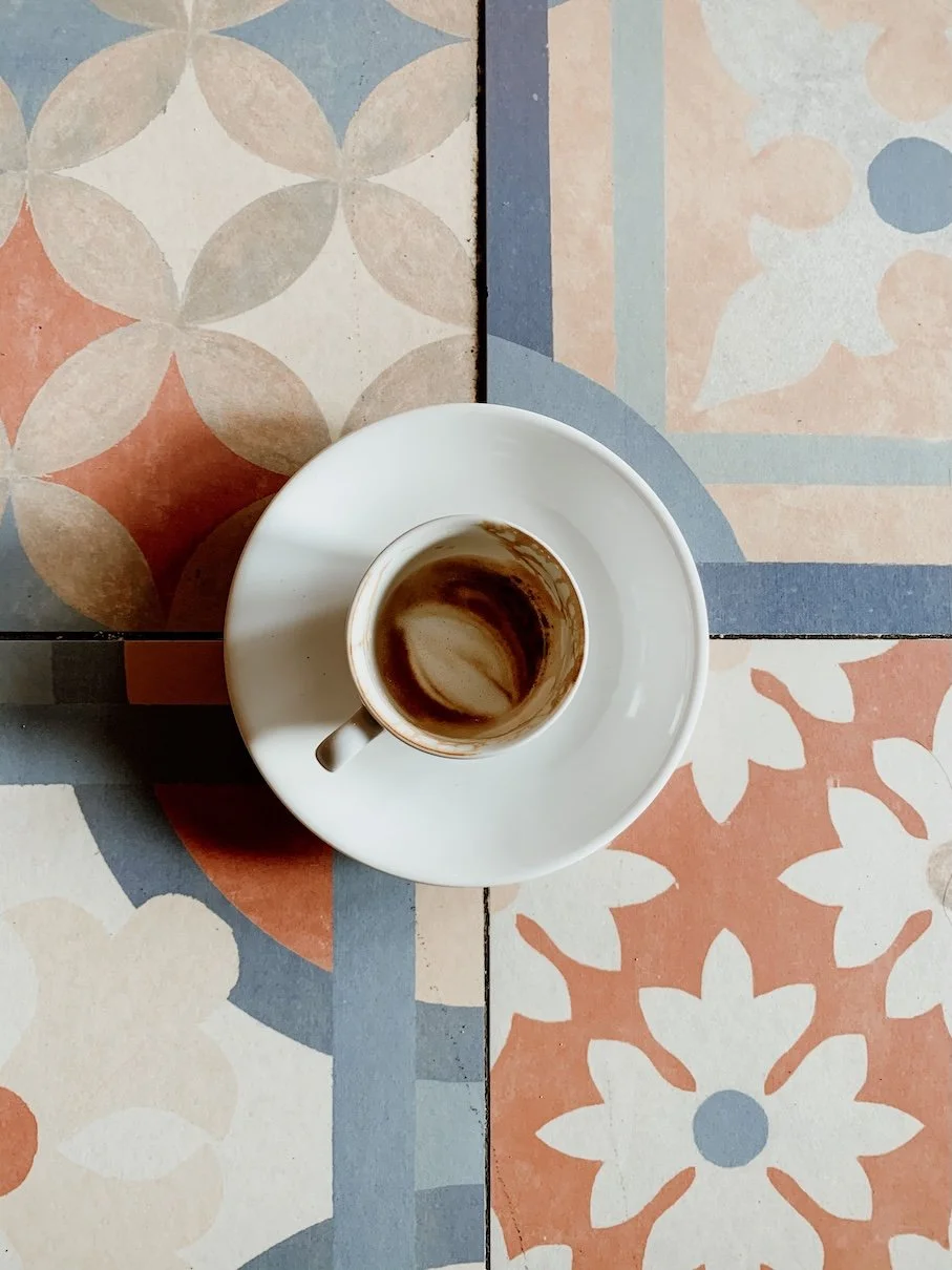 Coffee cup on colourful patterned tiles.