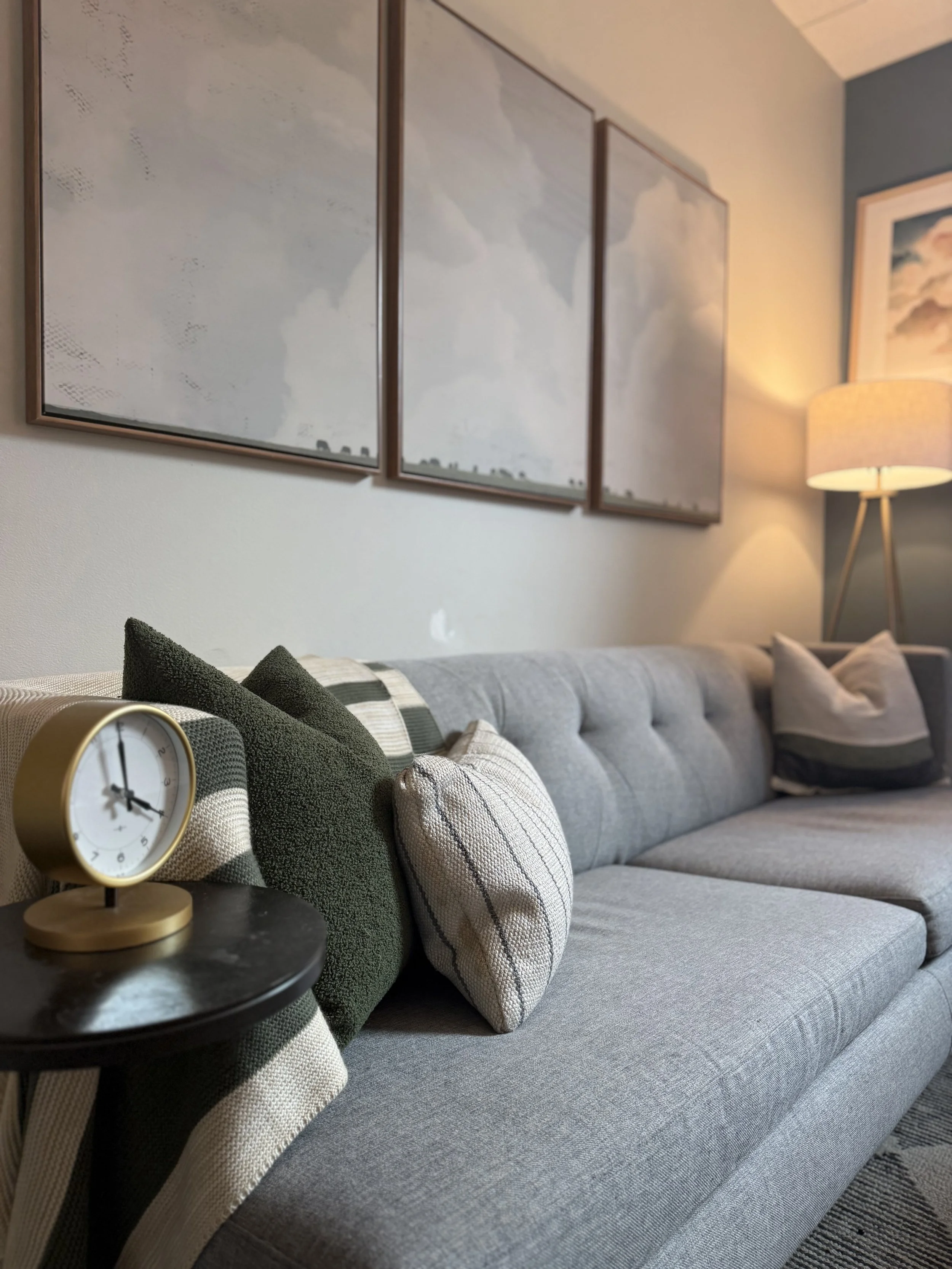Therapist office with gray couch, clock, lamp and pictures