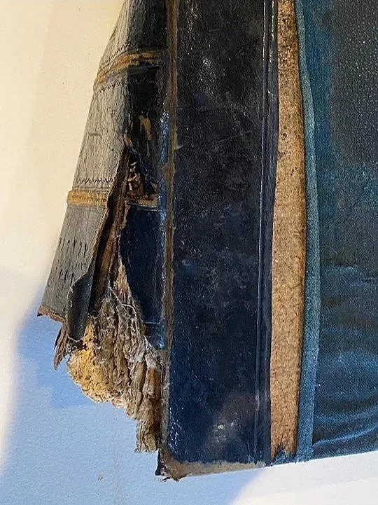 Frayed and torn pages of an old, worn-out book with a partially damaged cover.