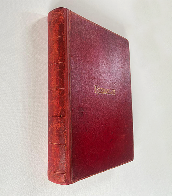 Close-up of a vintage red leather-bound book with gold lettering on the cover.