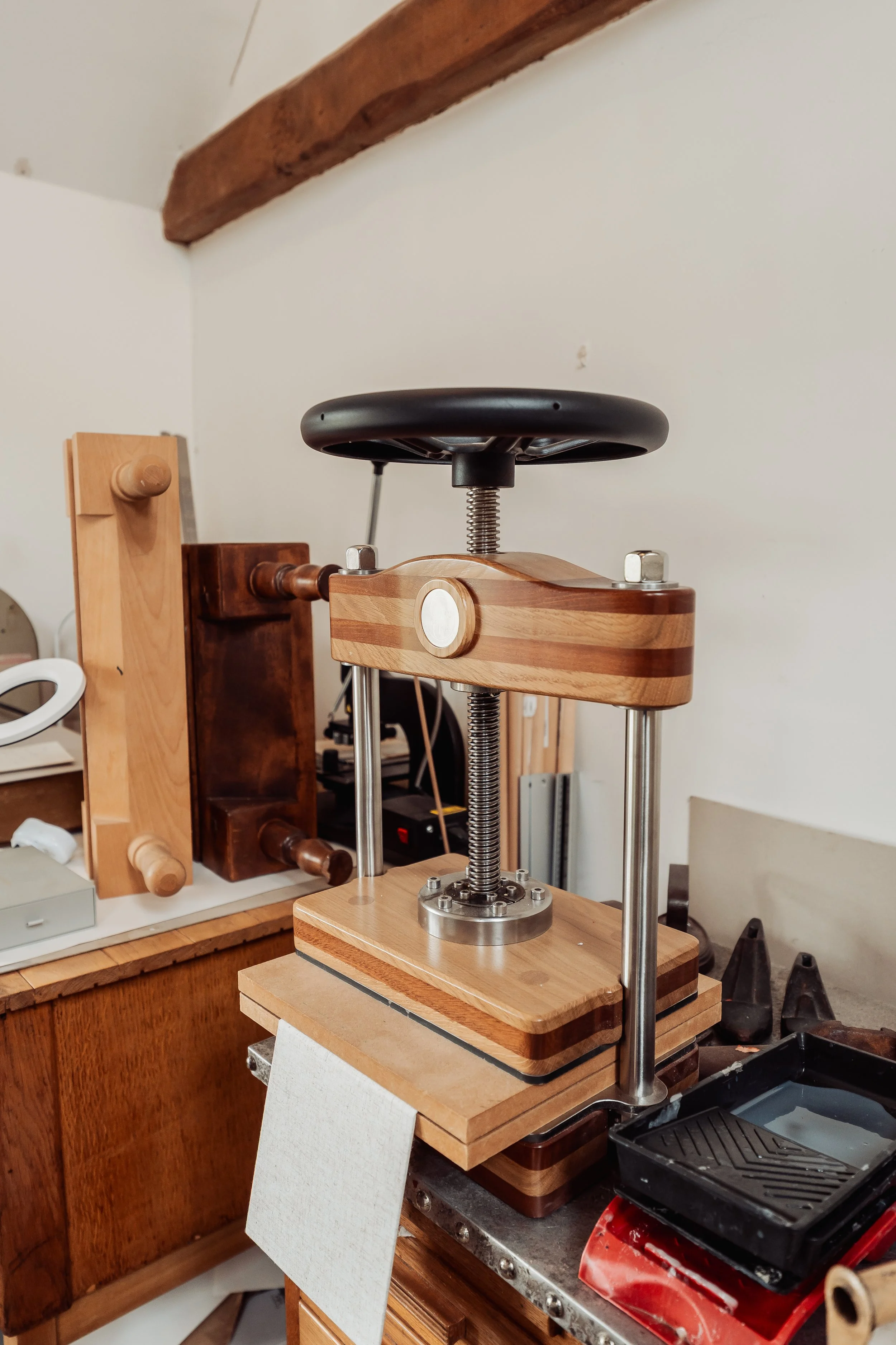 A setup for vinyl record cutting or engraving on a wooden workbench, including a turntable-like device with a metal arm and a sharp cutting tool, surrounded by various wood pieces and tools.
