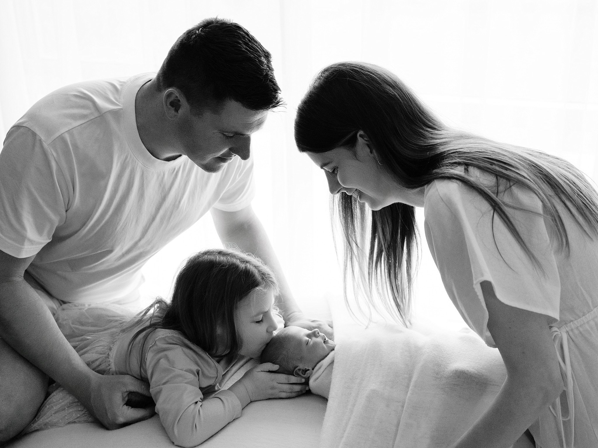 Black and white family portrait of parents and child gathered around their newborn baby, Sydney