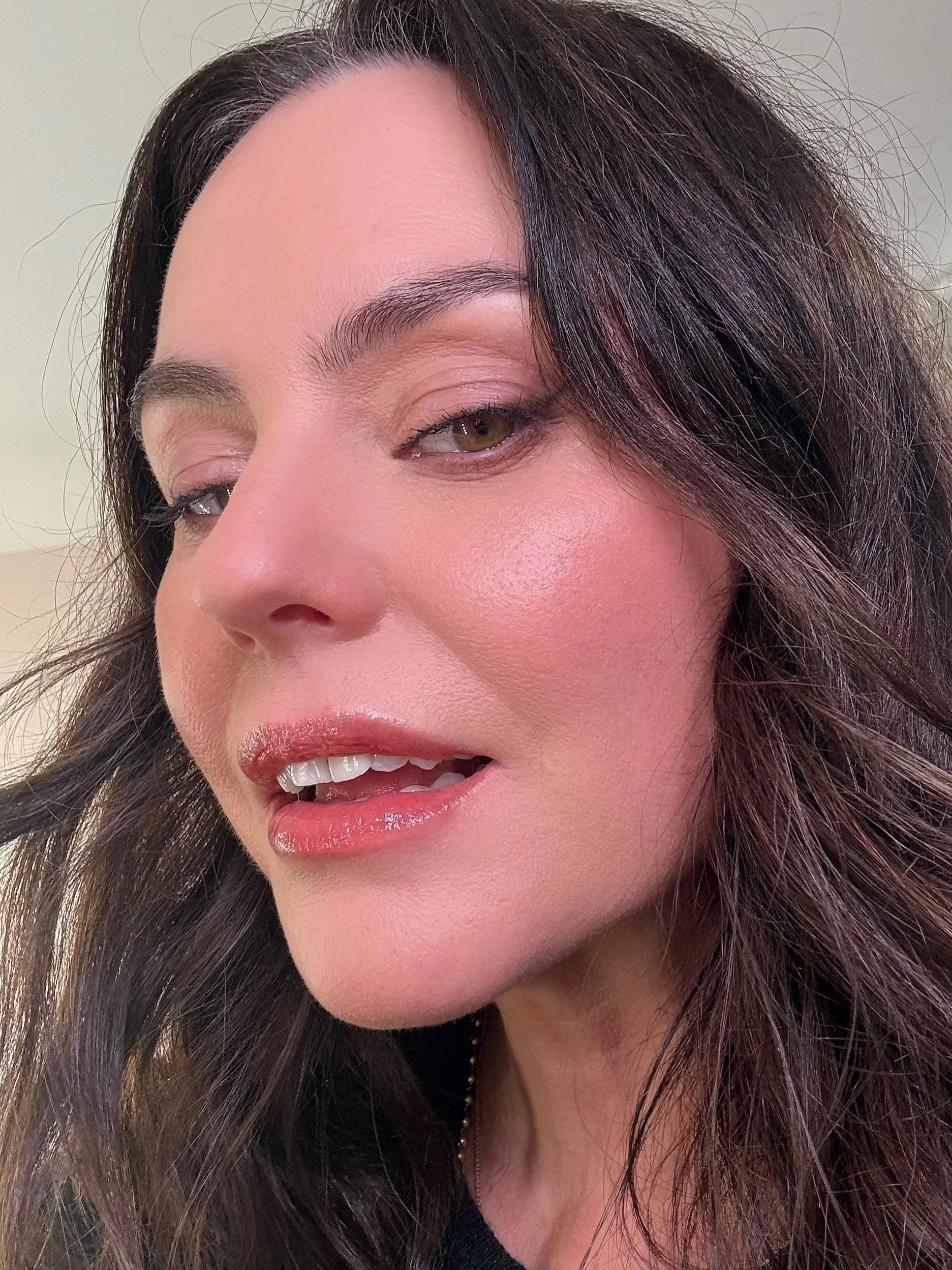 Close-up of a woman's face showing her eyes, nose, and lips with dark brown hair and makeup.