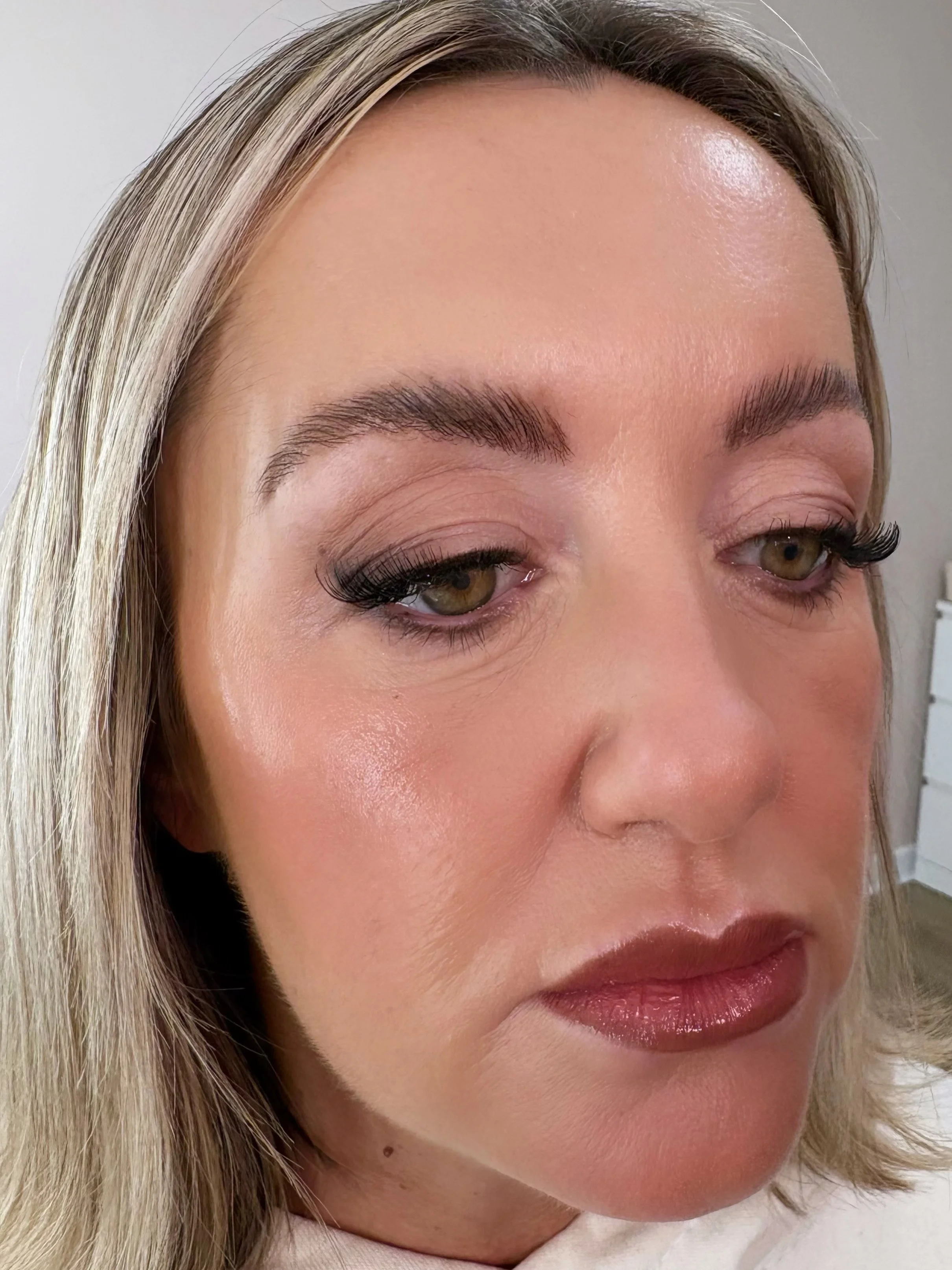 Close-up of a woman with blonde hair, brown eyes, and makeup, including dark eyeliner and lipstick.