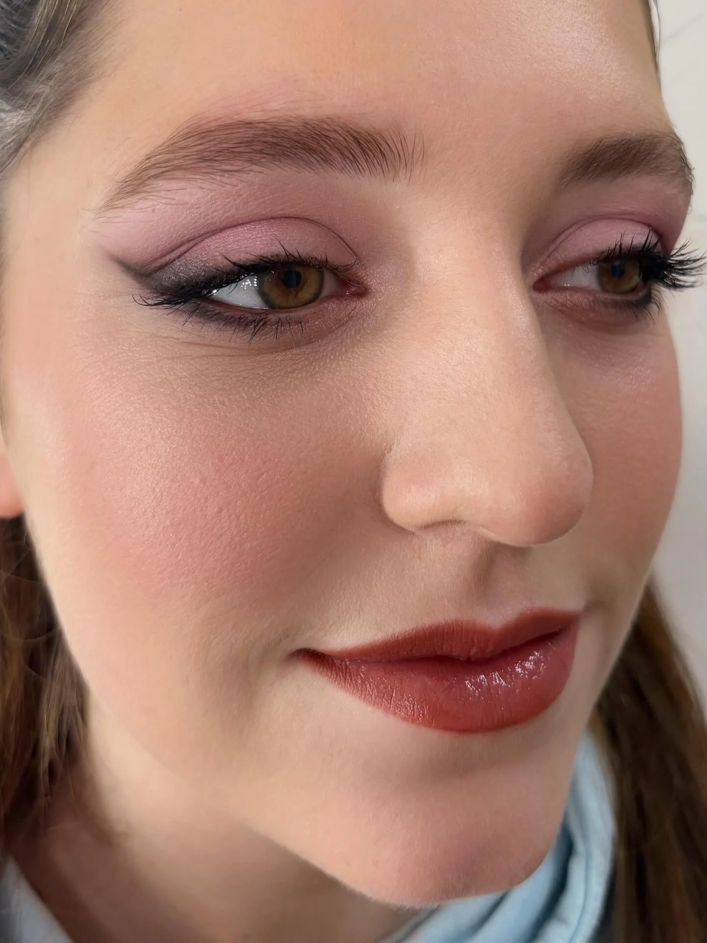 Close-up of a woman's face showing her eye makeup, eyebrows, and lips, with her eyes slightly closed.