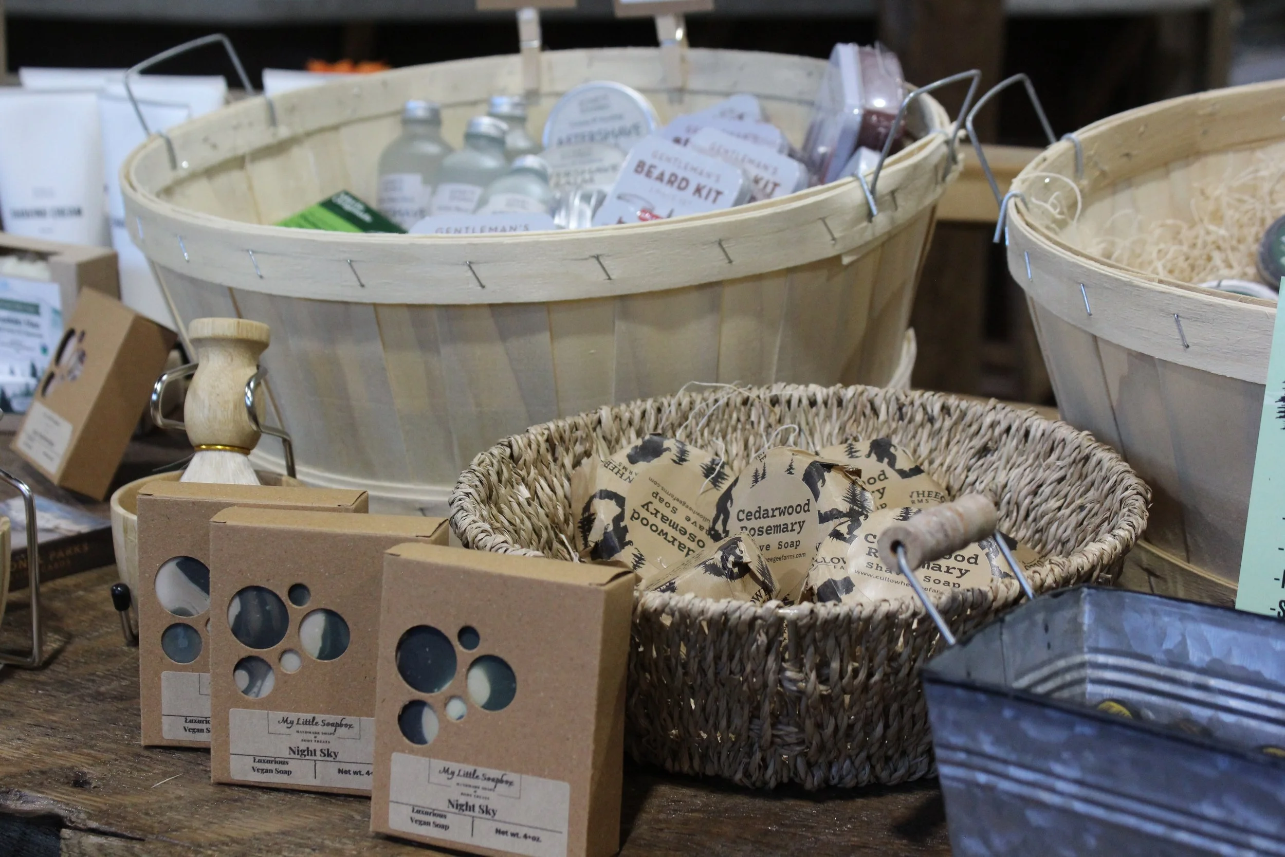 Display of various personal care and grooming products in baskets, including soap bars and beard grooming kits.