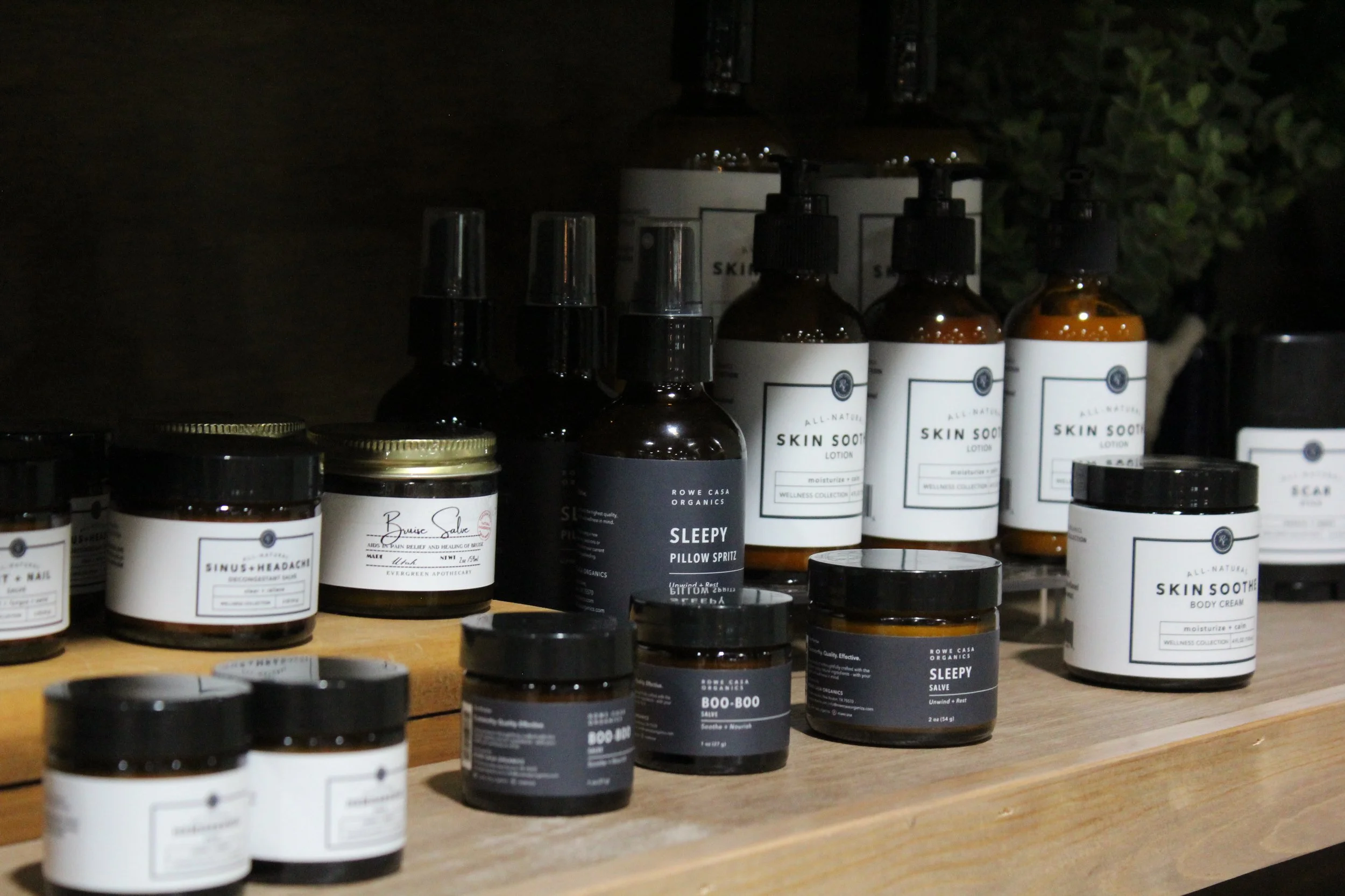 Organic skincare and wellness products, including lotions, creams, and sprays, arranged on shelves and a wooden table.