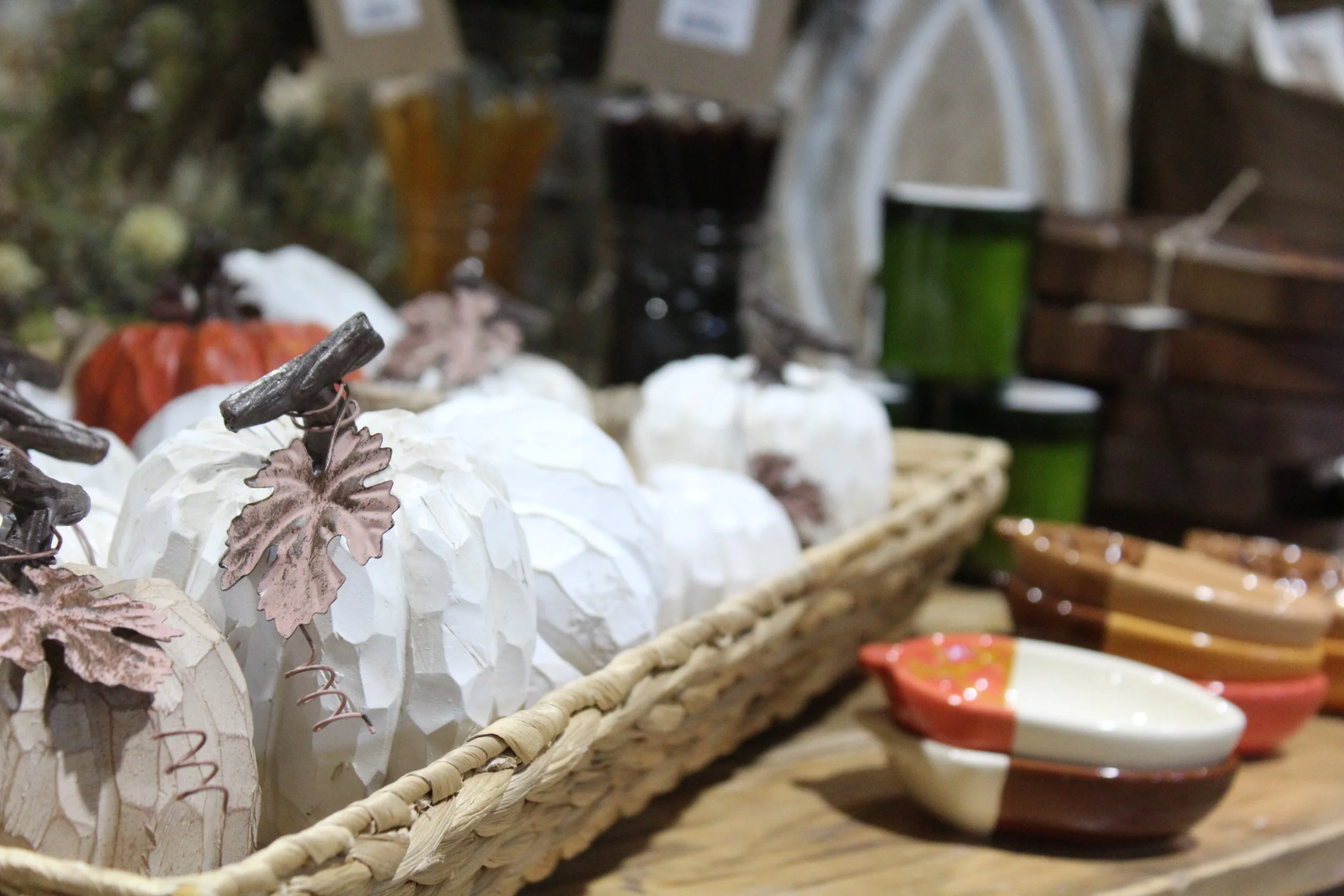 Decorative pumpkin with brown leaves and flower embellishments in a basket, autumn-themed display.