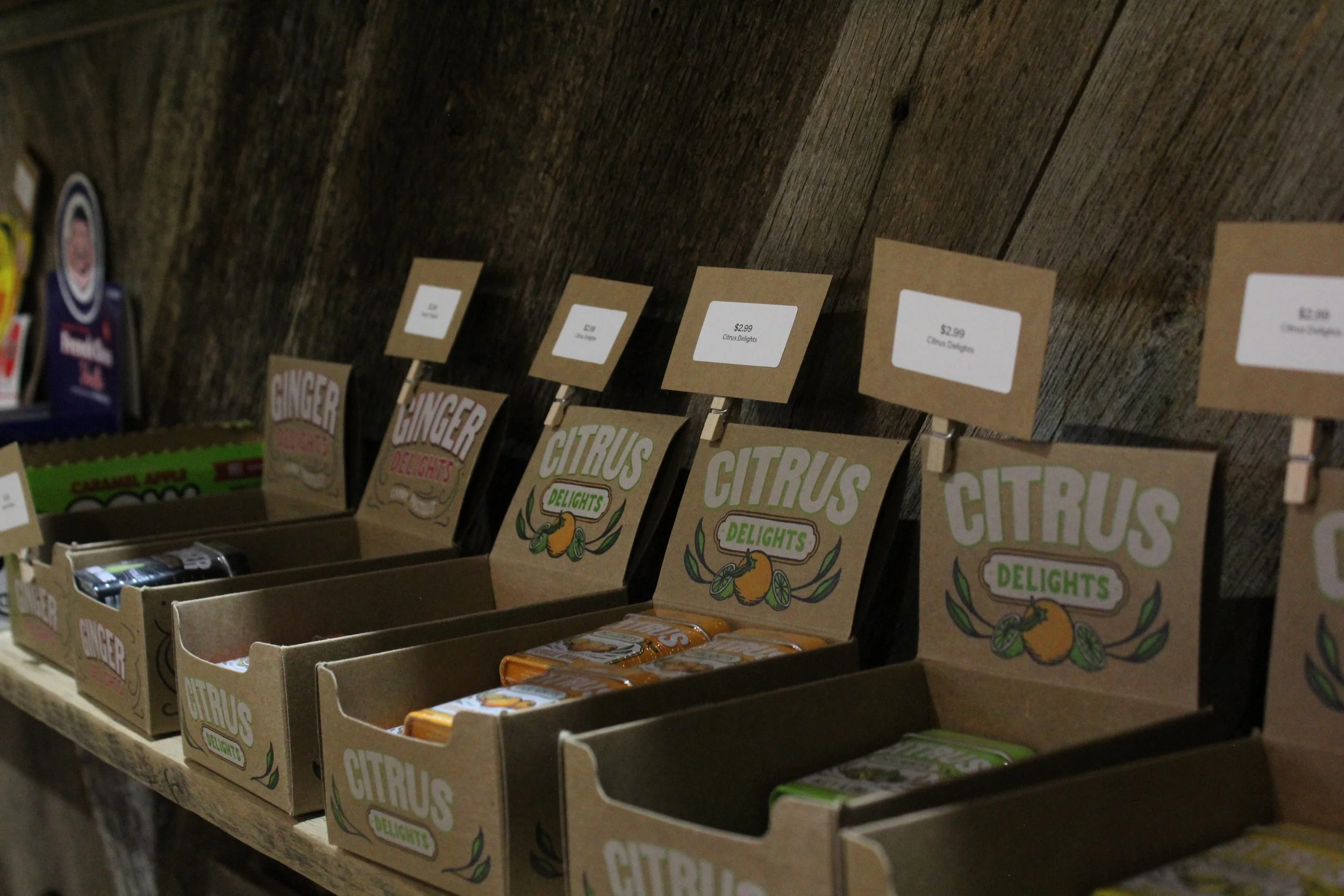 Display of boxes of citrus-flavored candies labeled 'Ginger Delights' and 'Citrus Delights' at Burley Sustainable General Store in West Jefferson, NC.