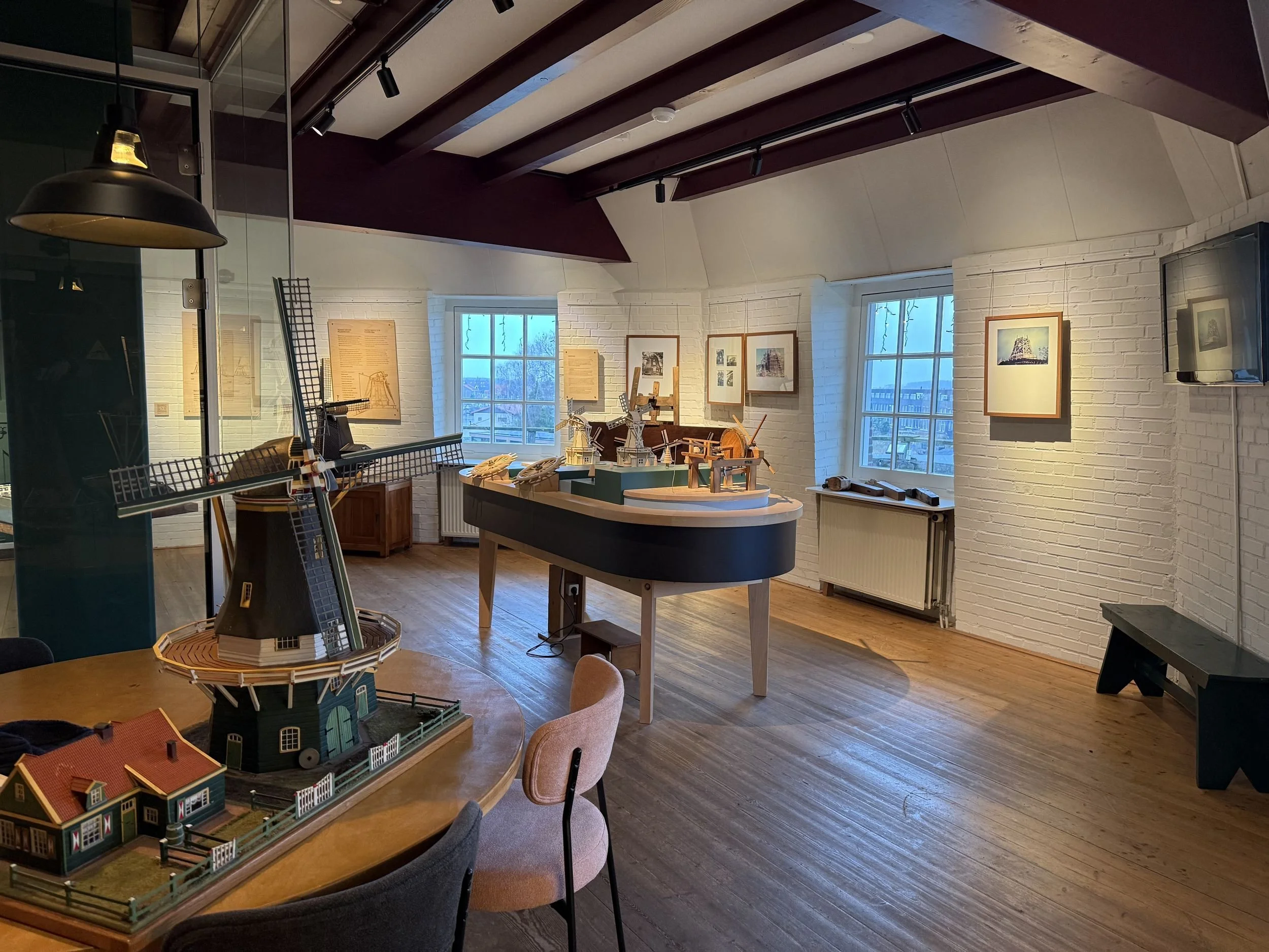 Museum room with a windmill model and canal-side windows in Amsterdam