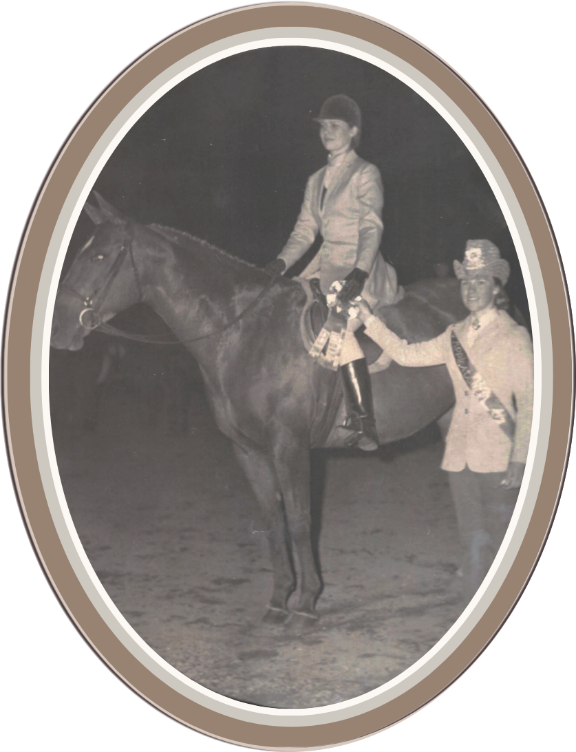 Black and white photo of a Linda Anne Starr riding a horse at a night event, holding a ribbon, with a woman standing next to the horse smiling. Linda Anne Starr | Training the Horse's Beautiful Mind
