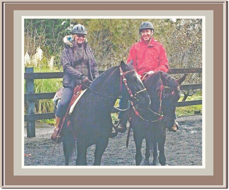 Linda Anne and husband Ken Starr,  riding horses on a trail with a wooden fence and trees in the background. Linda Anne Starr | Training the Horse's Beautiful Mind