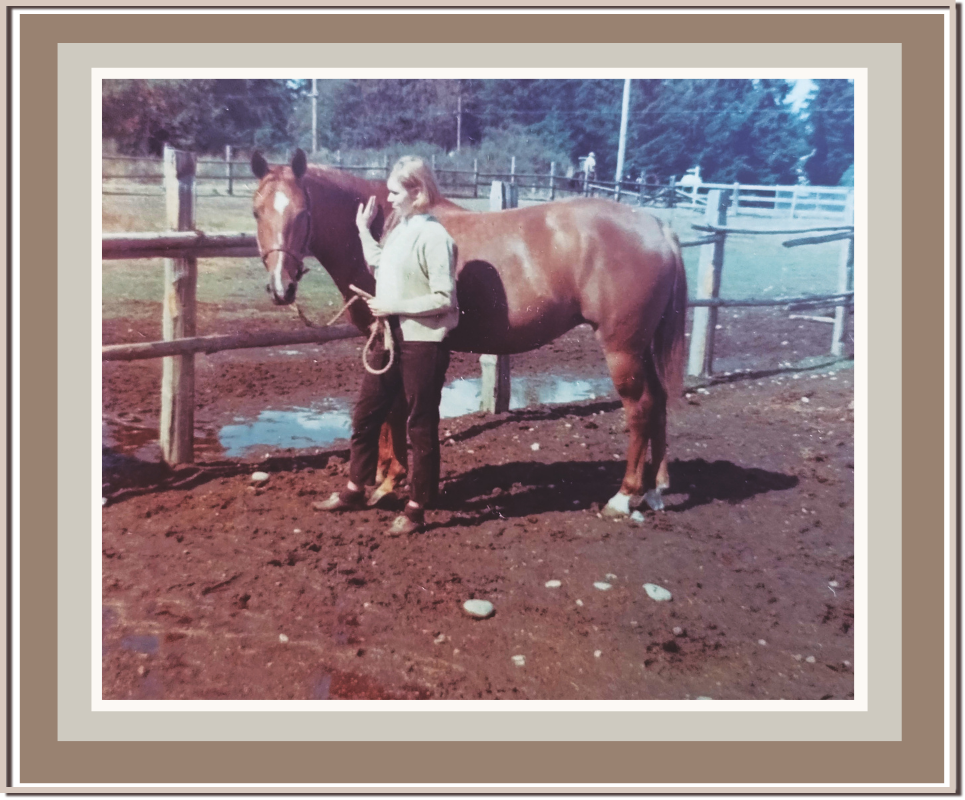 Linda Anne Starr standing next to a brown horse on a dirt field, holding a rope, with paddocks and trees in the background. Linda Anne Starr | Training the Horse's Beautiful Mind