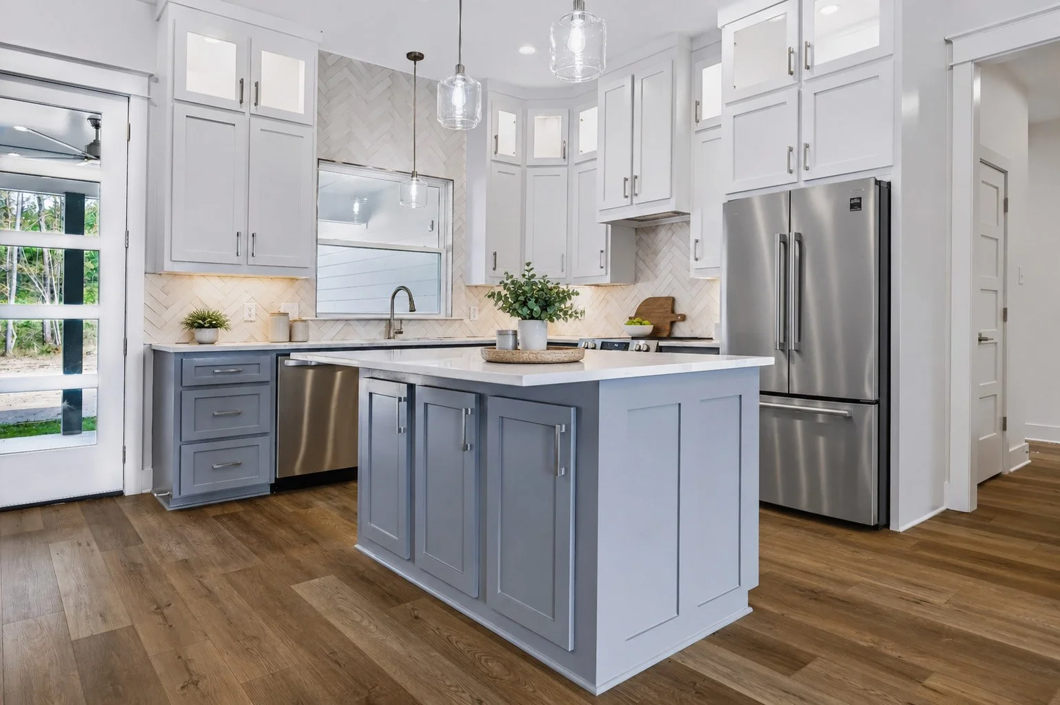 Modern kitchen with white cabinetry, stainless steel appliances, and light wooden flooring.