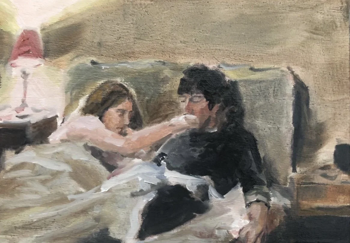A woman helping a man drink water in bed, with a bedside lamp and a clock nearby.