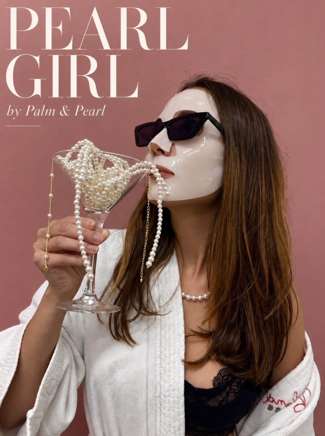 A woman wearing sunglasses and a pearl necklace, holding a martini glass filled with pearl necklaces, with some necklaces draped over her face and hand, against a pink background.