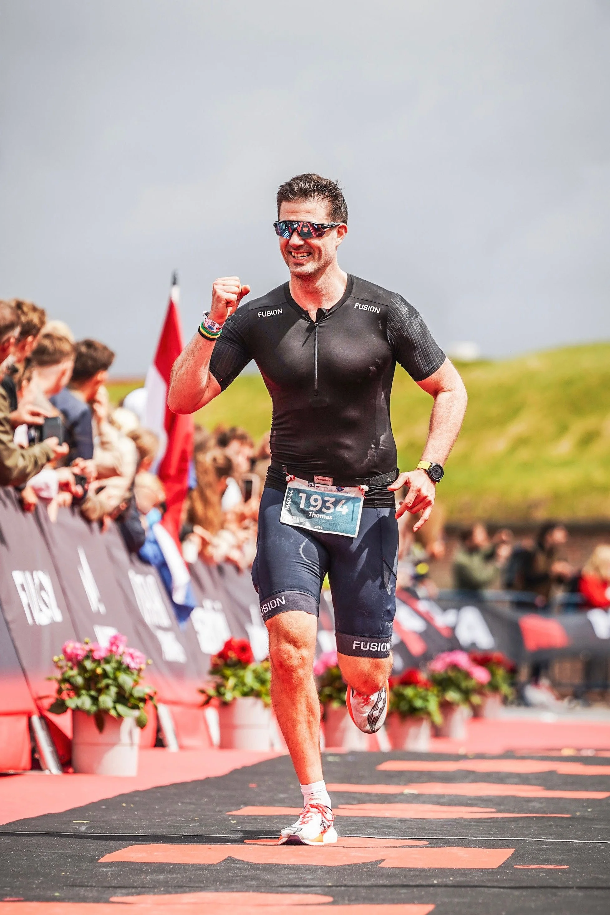 Personlig Træner Thomas Hansen løber IRONMAN og passerer målstregen med armen i vejret.