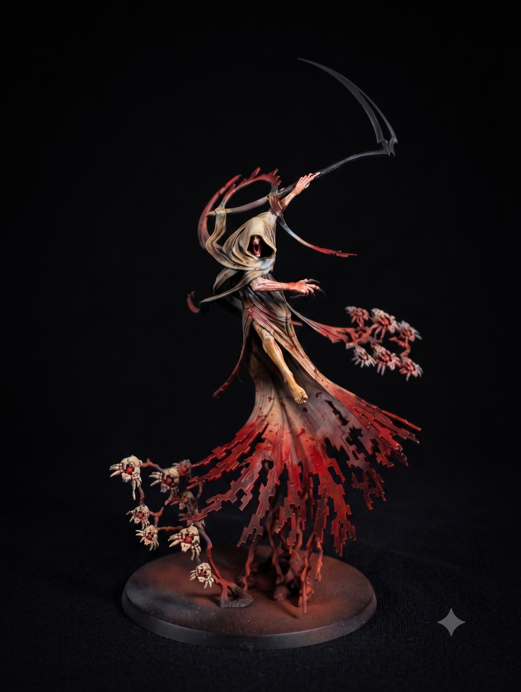Miniature figurine of a skeletal figure with a hood, holding a scythe, standing amidst red, leafless trees and smaller skull-like structures on a round base.
