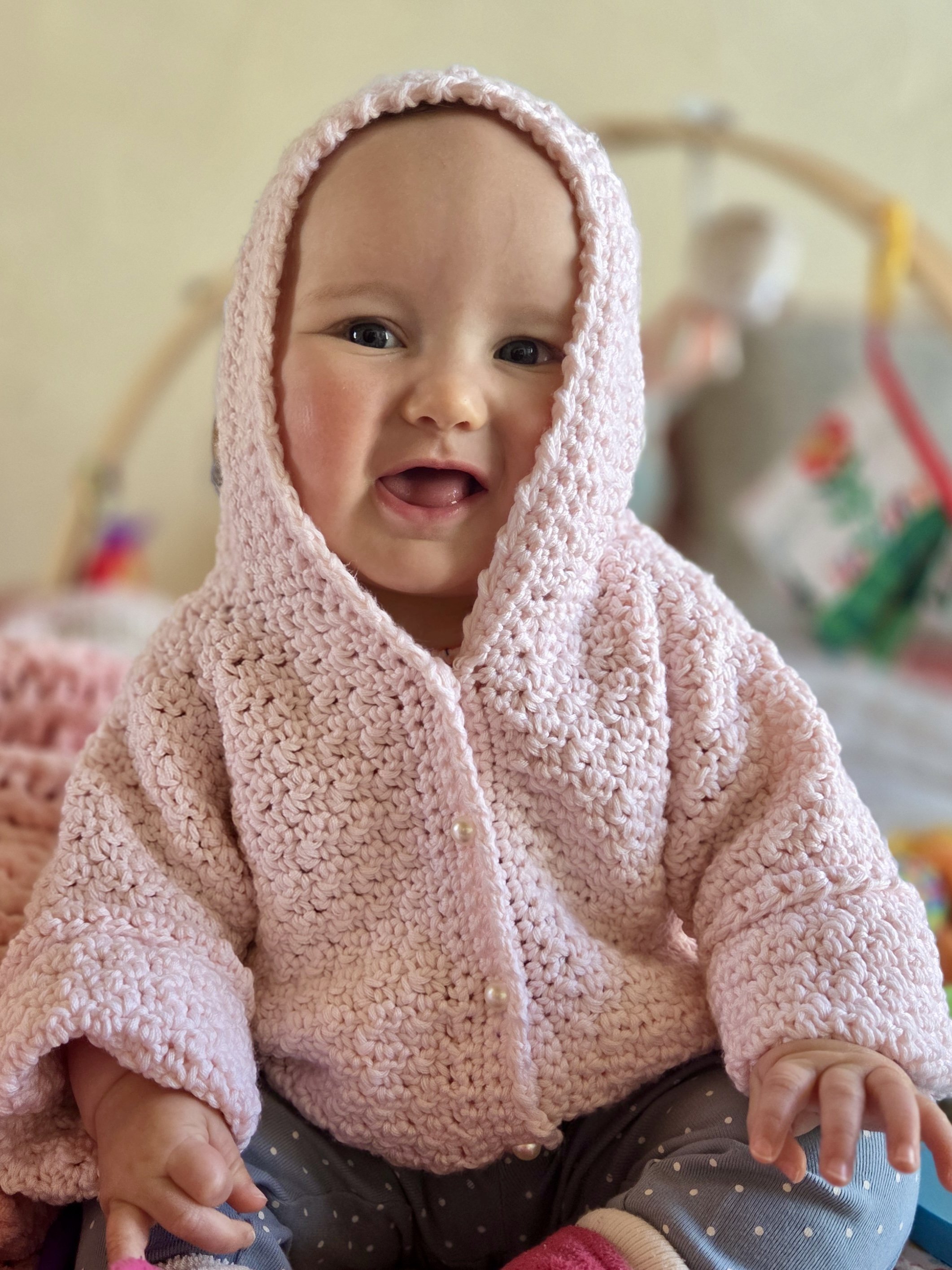 A young child wearing a pink crochet sweater created by Tessa Smith Designs.