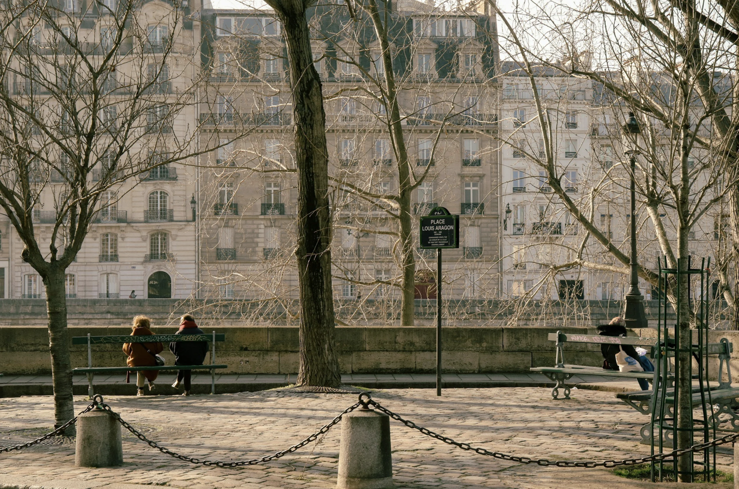 Seine promenade in Paris with trees, benches, and historic apartment buildings