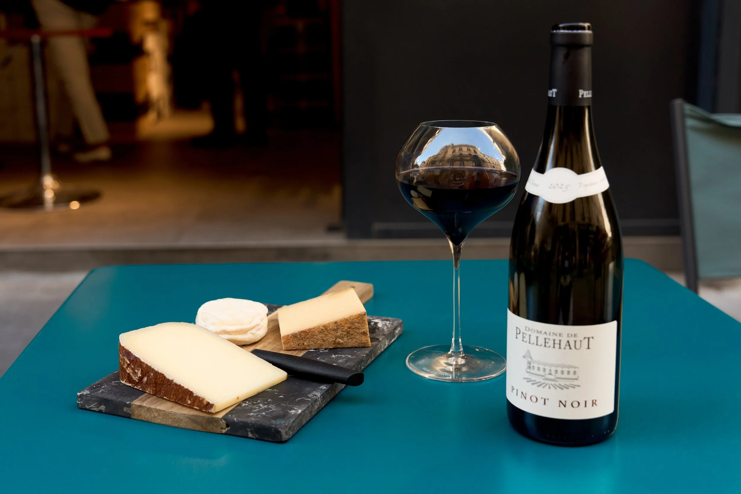 French Pinot Noir with a glass of red wine, cheese, and bread on a Paris tasting table