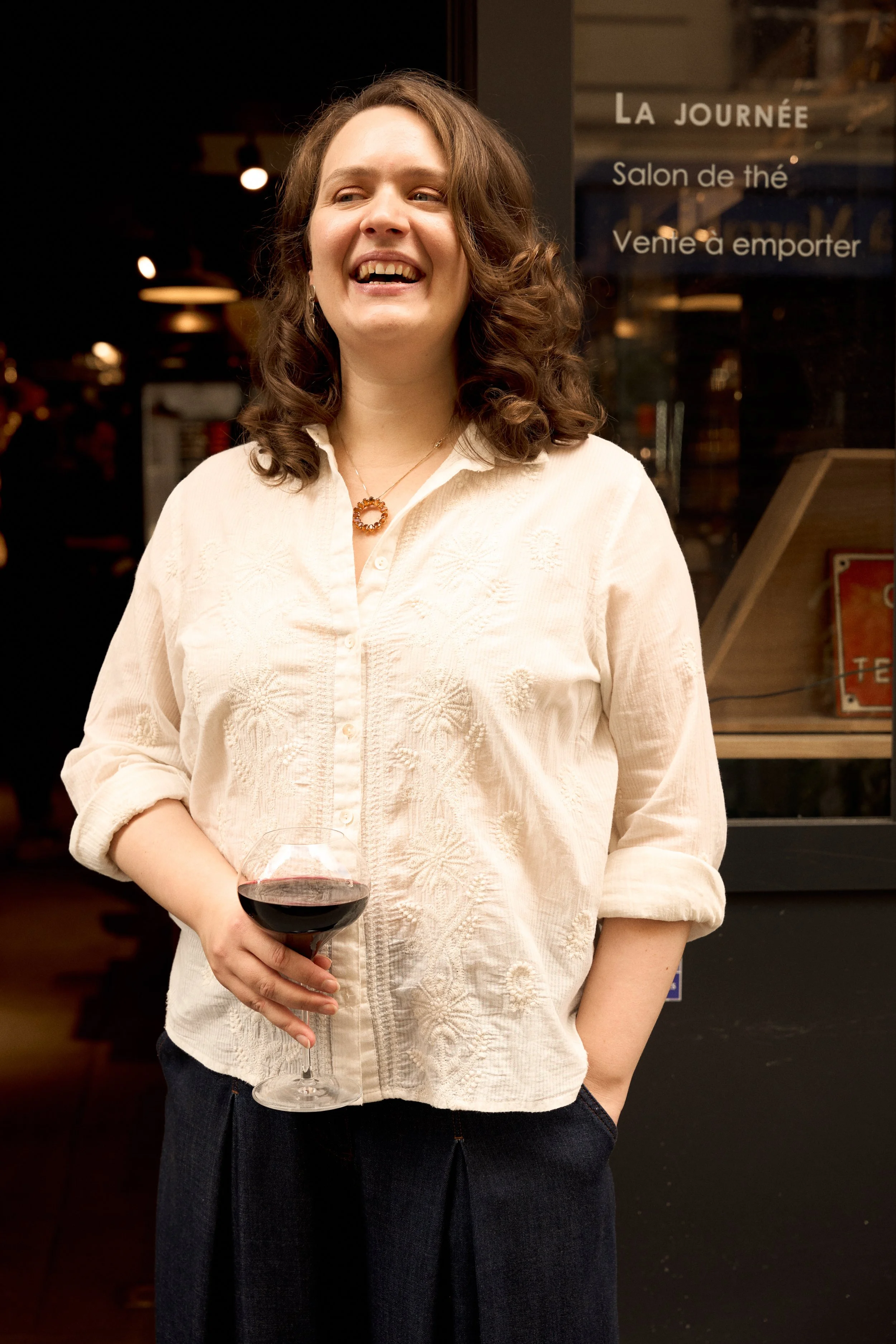 Leopoldine smiling and holding a glass of wine in Paris