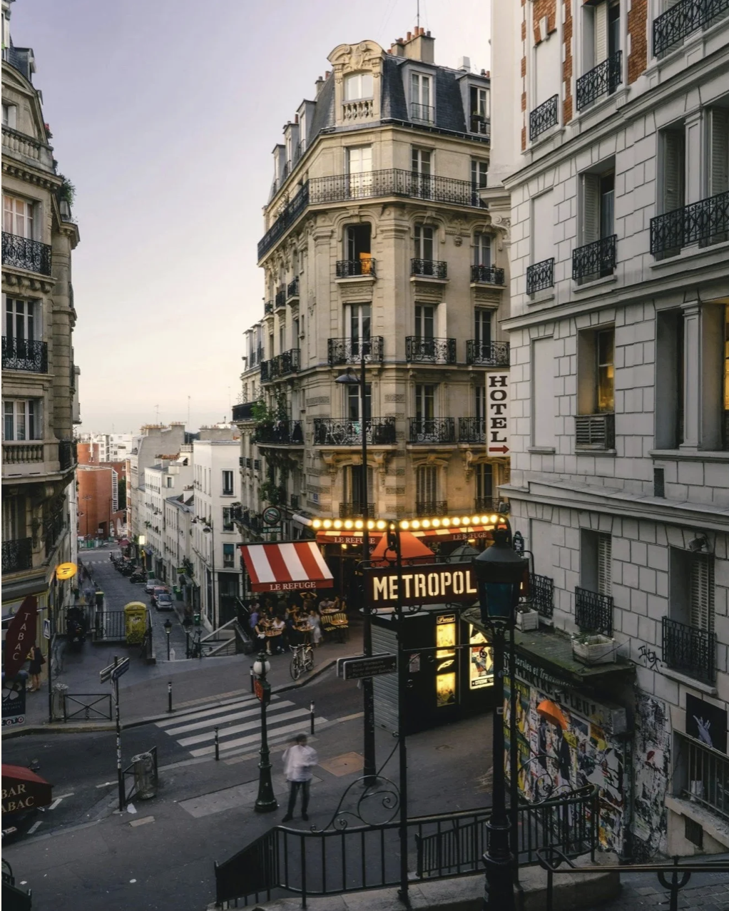 Paris street with Haussmann buildings, a Metro entrance, and a café terrace