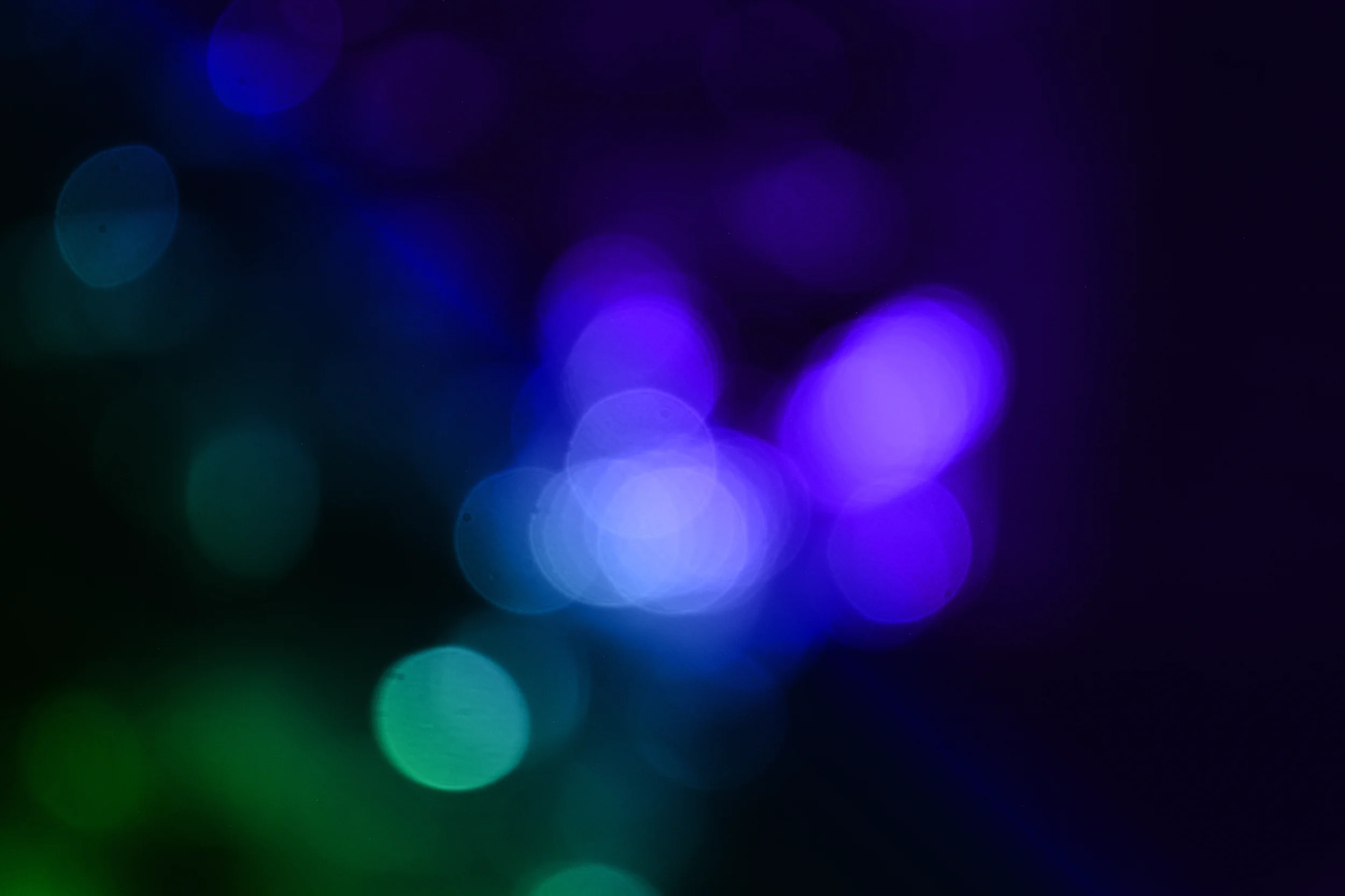 Abstract background with colorful bokeh lights in blue, purple, and green hues.