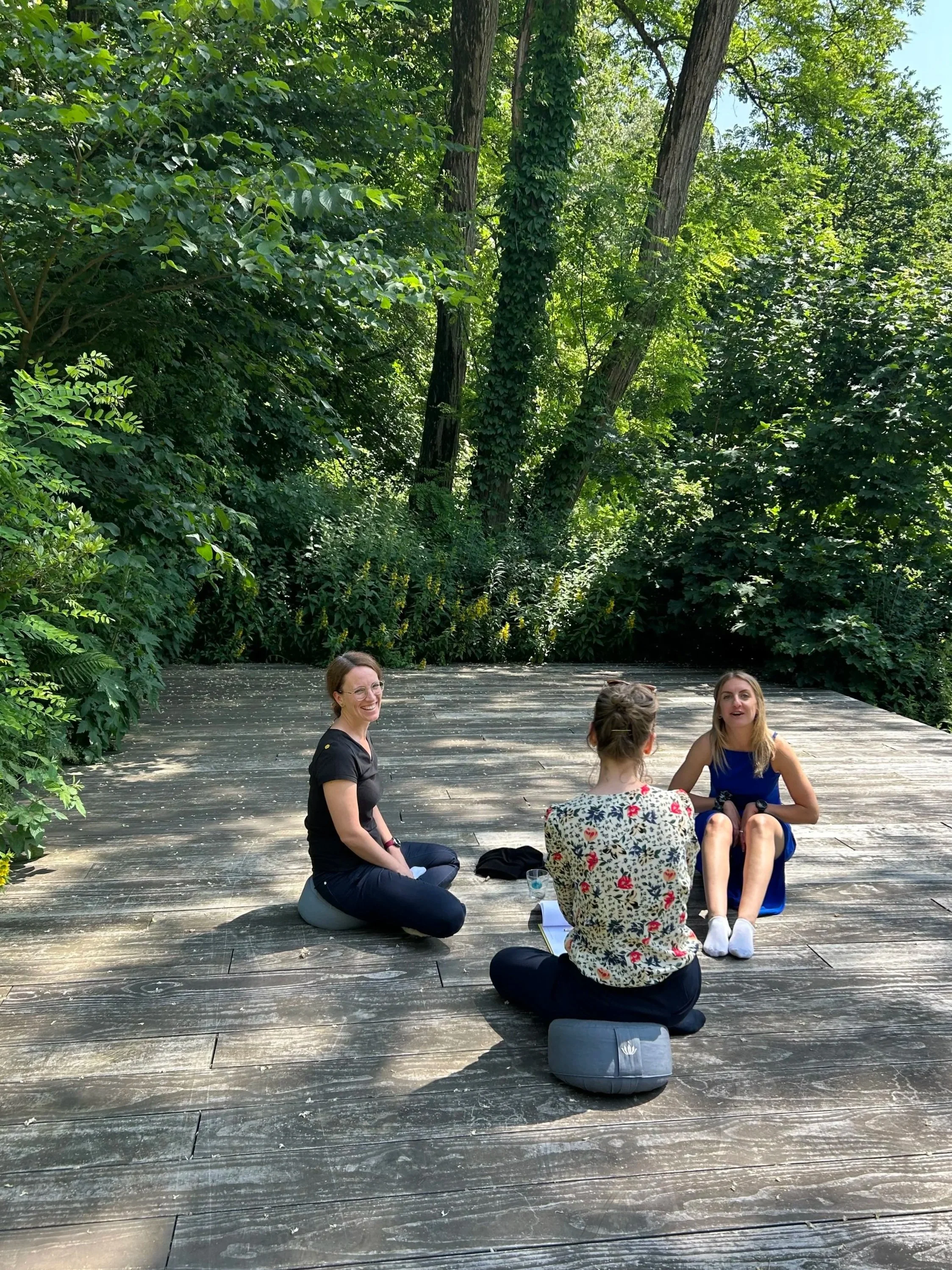Three professional women sitting down outside on emotional intelligence retreat