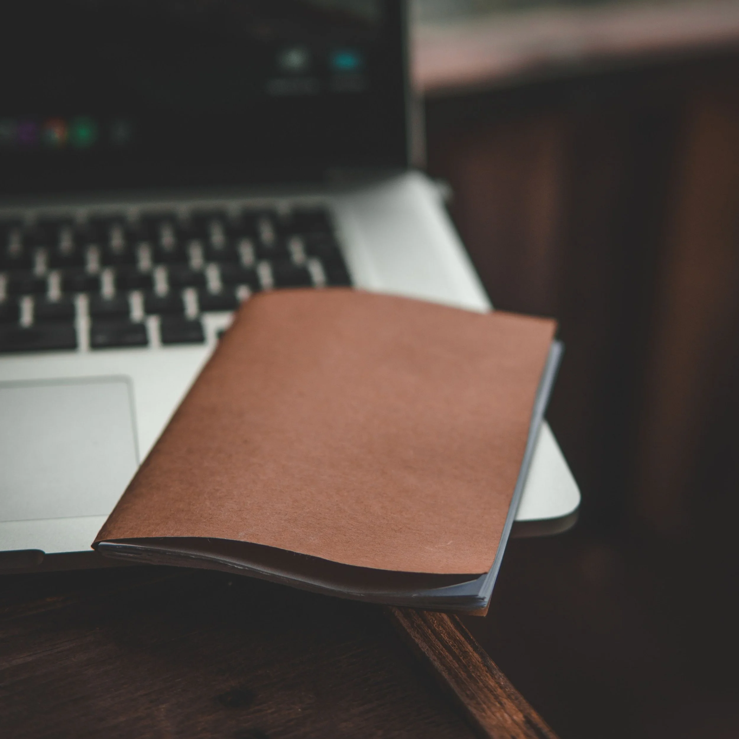 open laptop and brown research notes book