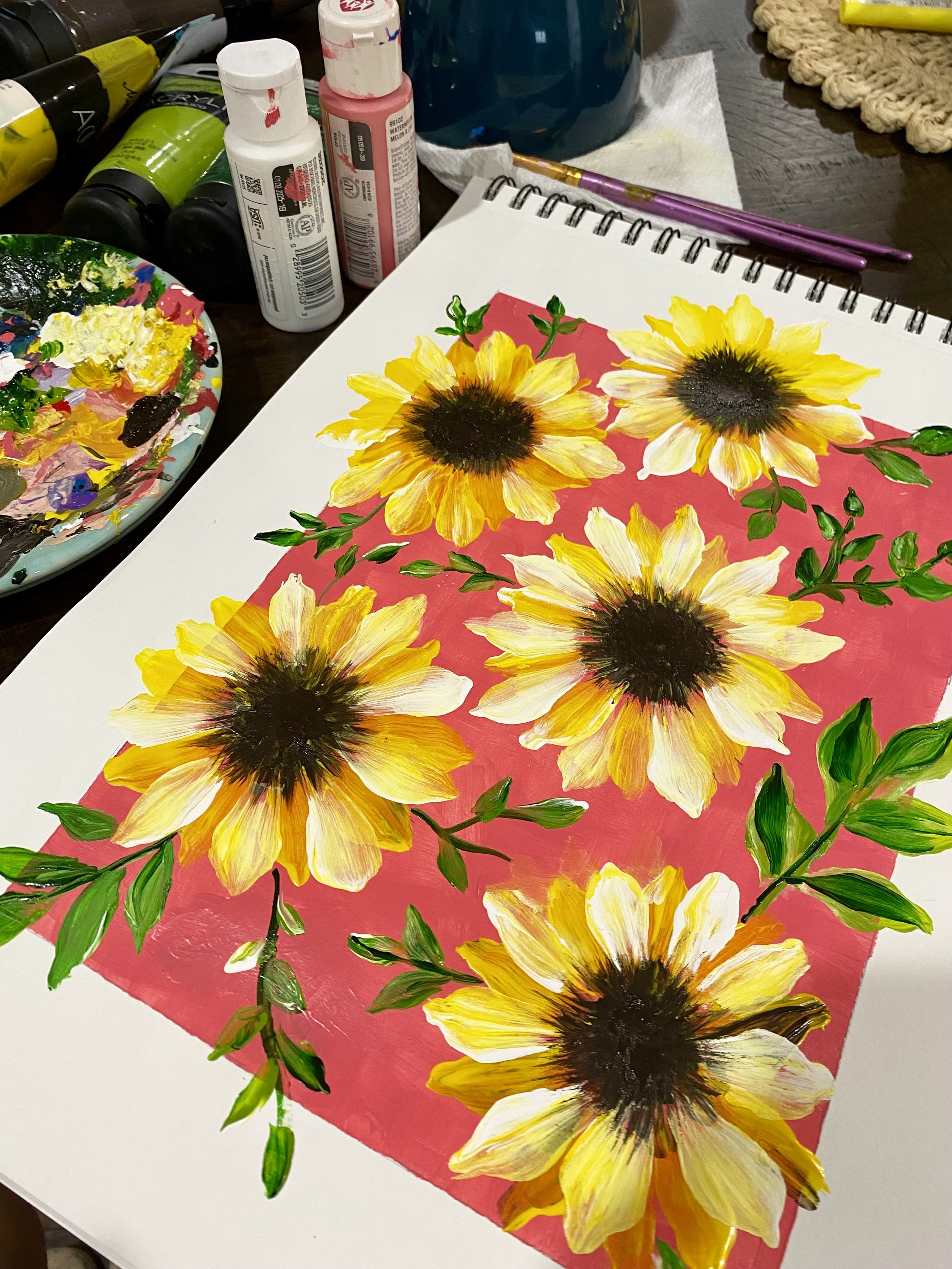 A painting of yellow sunflowers with green leaves on a pink background.