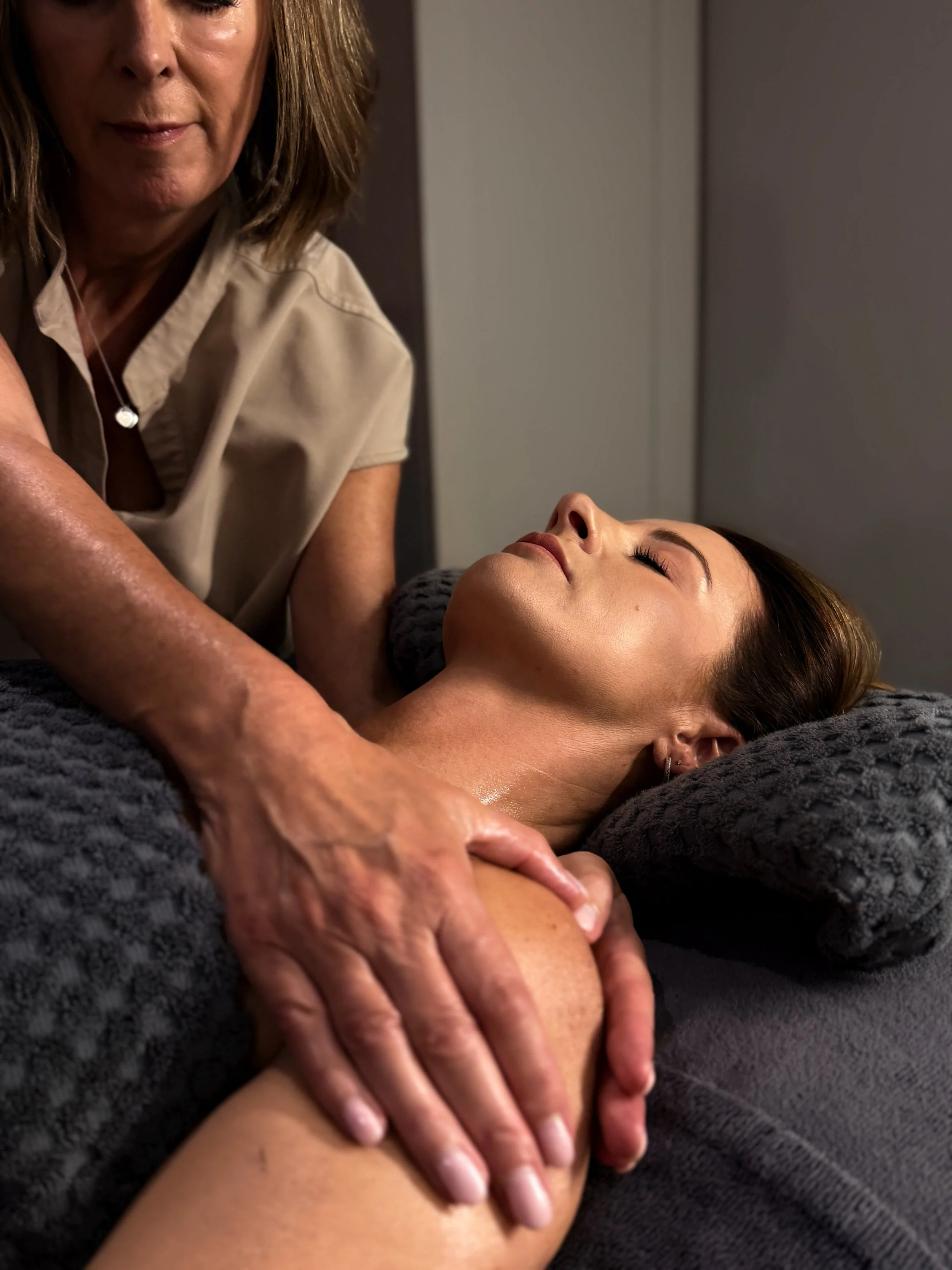 A woman receiving a massage from a masseuse.