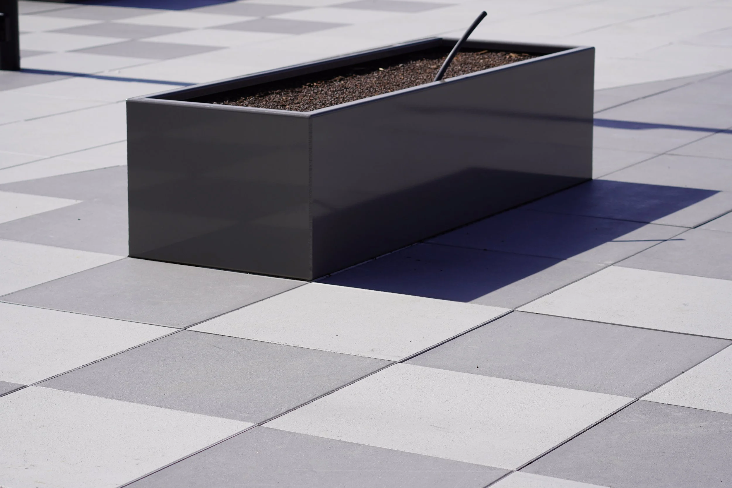 Rooftop amenity patio with metal planter boxes and checkered pavers at The Current apartment community, installed by 4G Paving