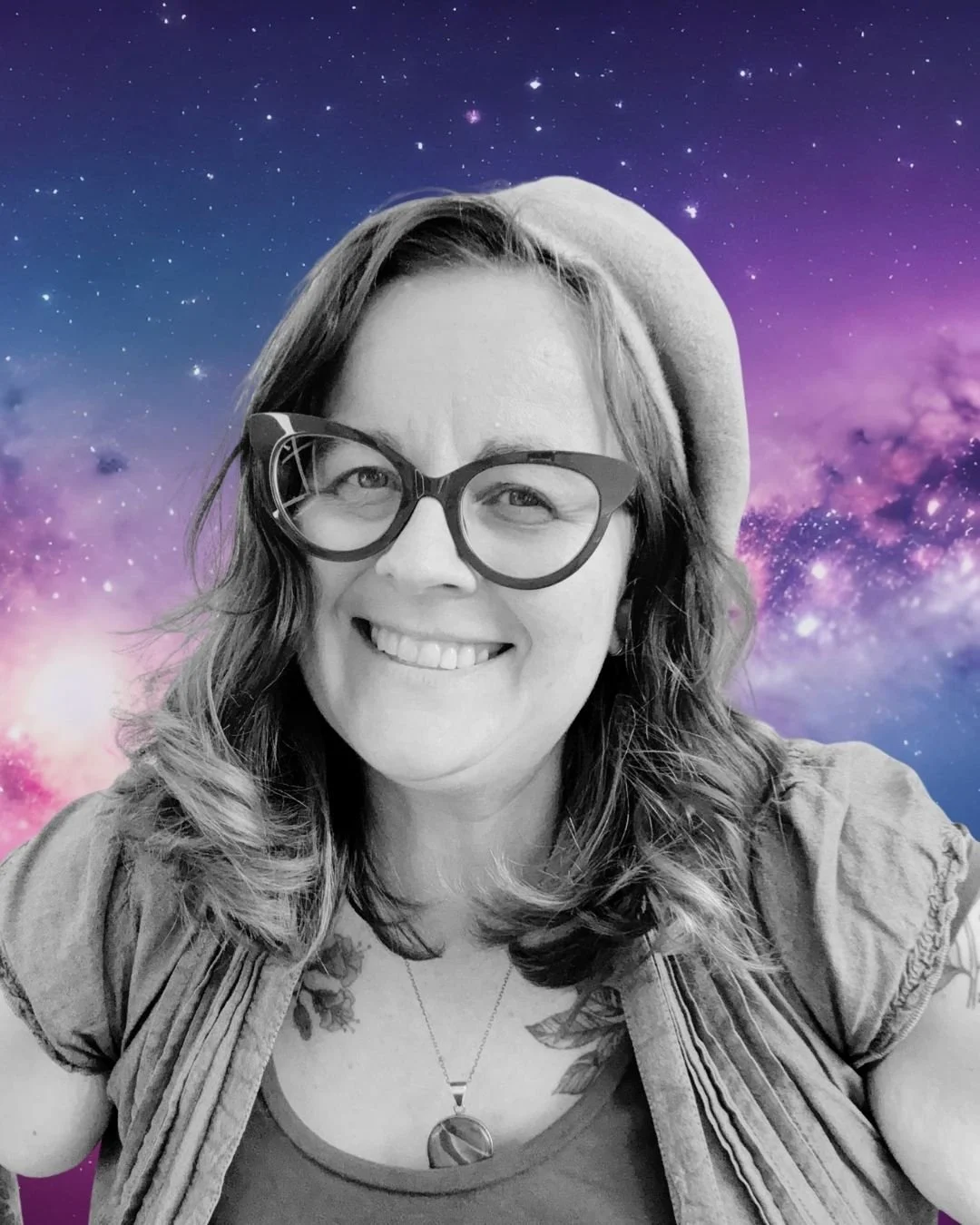 A smiling woman with wavy hair, wearing large glasses, a beanie, and a necklace, in front of a colorful galaxy background.