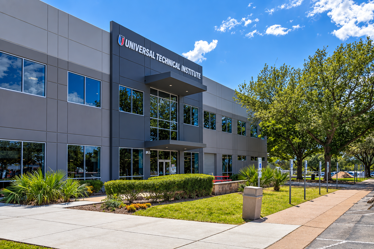 Exterior view of Universal Technical Institute building with trees, parking area, and a blue sky with clouds.