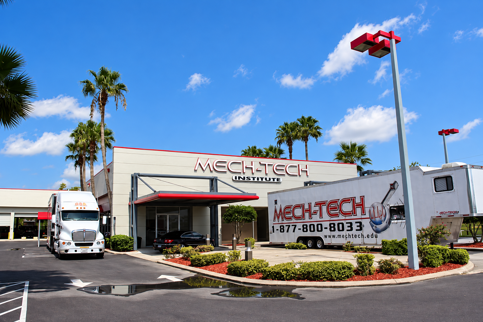 Exterior view of Mech-Tech Institute building with a large trailer parked outside, palm trees, and a bright blue sky with clouds.