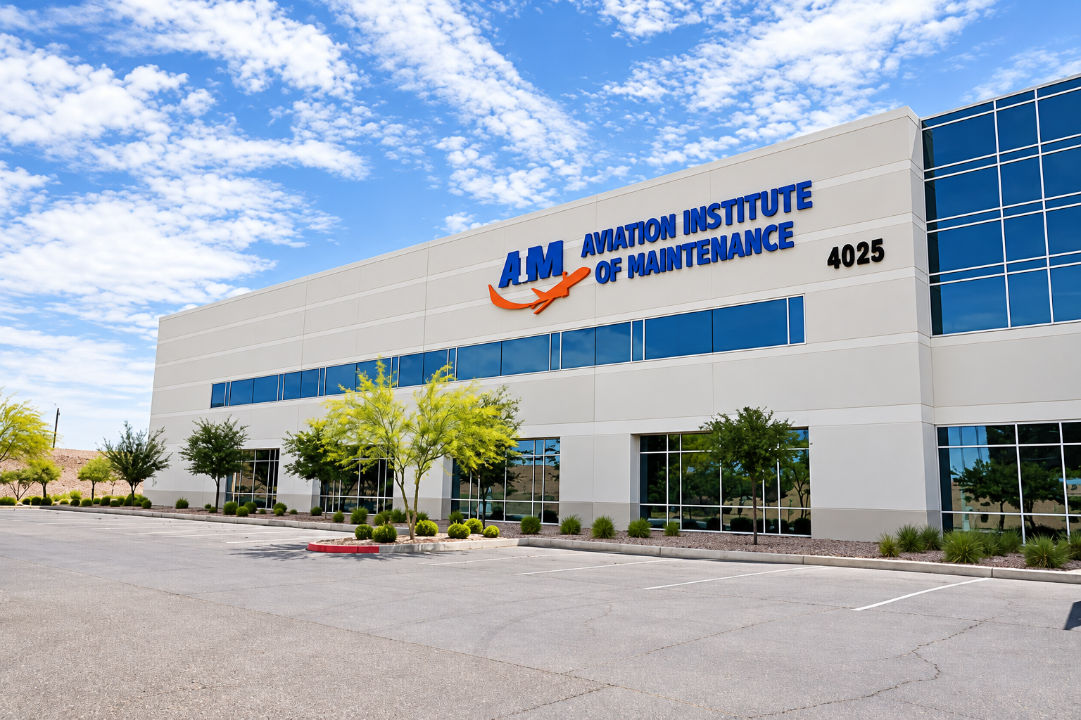 A modern commercial building with a sign that reads 'Aviation Institute of Maintenance' and the initials 'AIM.' The building has white exterior walls, blue-tinted windows, and a parking lot in front. There are trees and landscaping along the sidewalk under a partly cloudy sky.