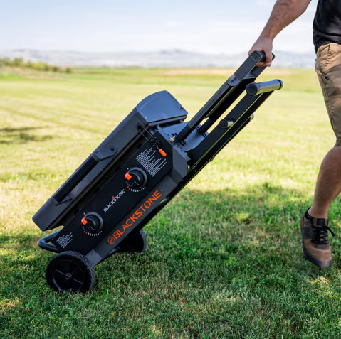A person using a Blackstone electric golf trolley on a grassy field.