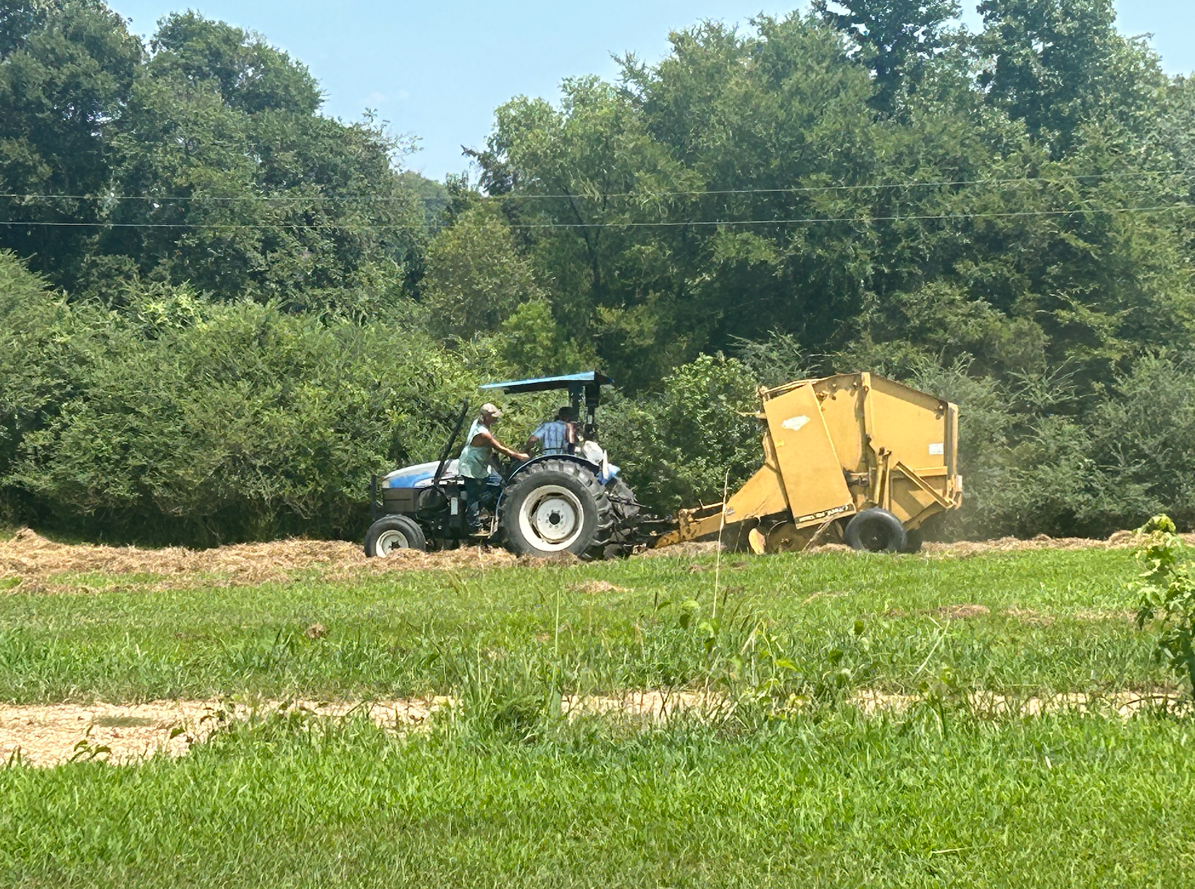 People working on a farm using a tractor to harvest or till the land.