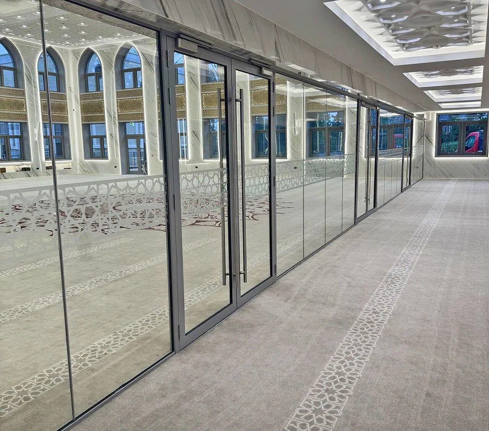 Modern interior space with glass sliding doors, tiled flooring, and arched windows with landscaping visible outside.