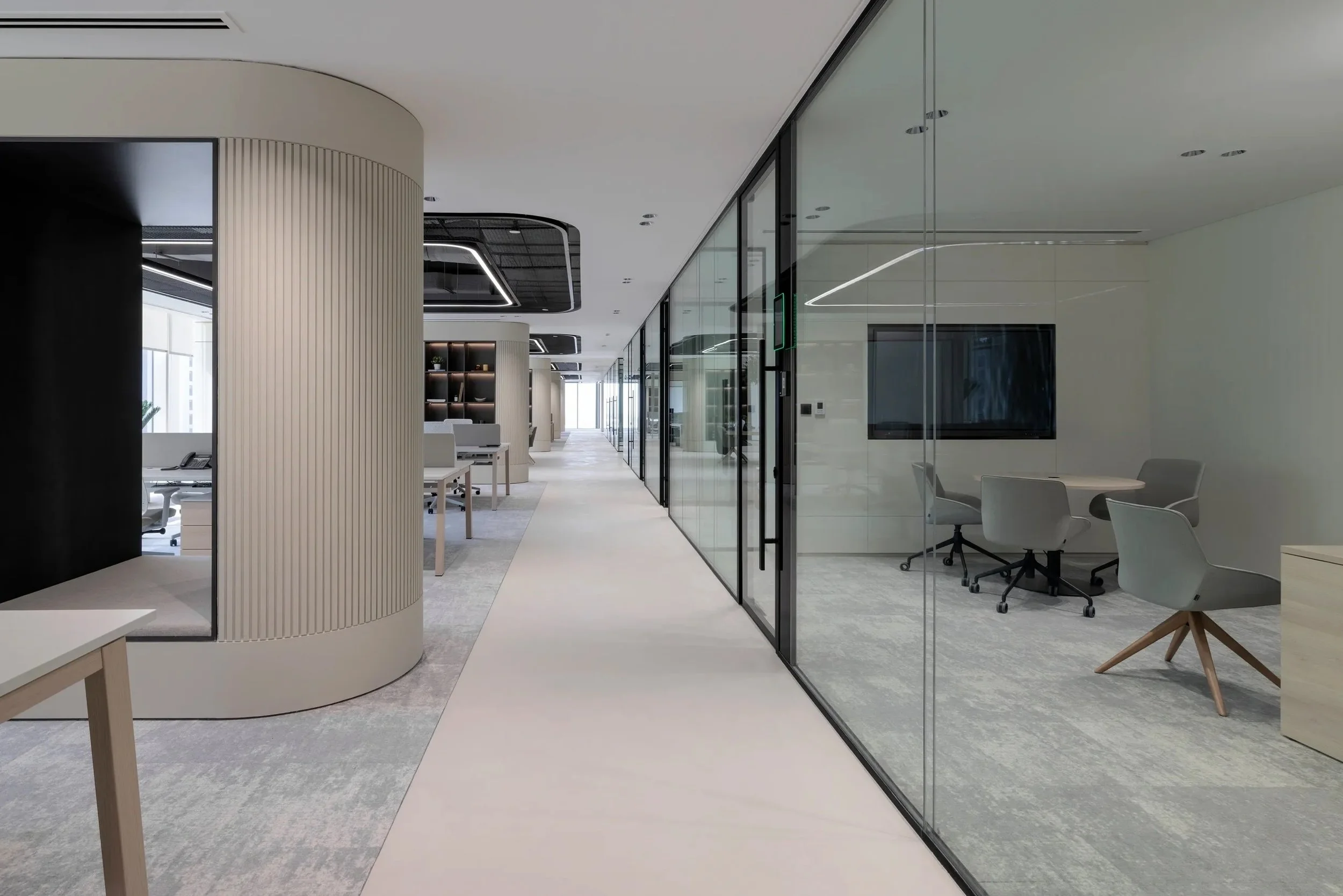 Modern office interior with glass partitions, workspaces, and minimalist design elements.