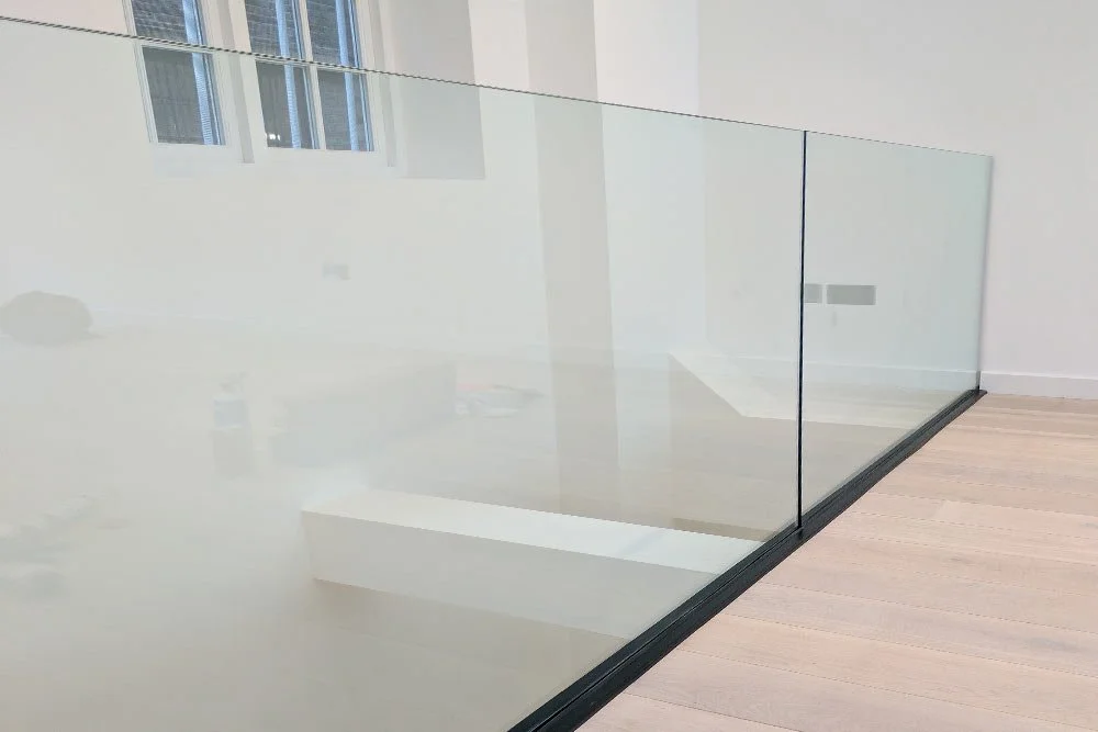 Empty room with a glass wall or railing and wooden flooring.