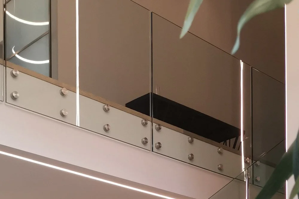 View of a modern indoor balcony with glass and metal railings, part of a building's interior.