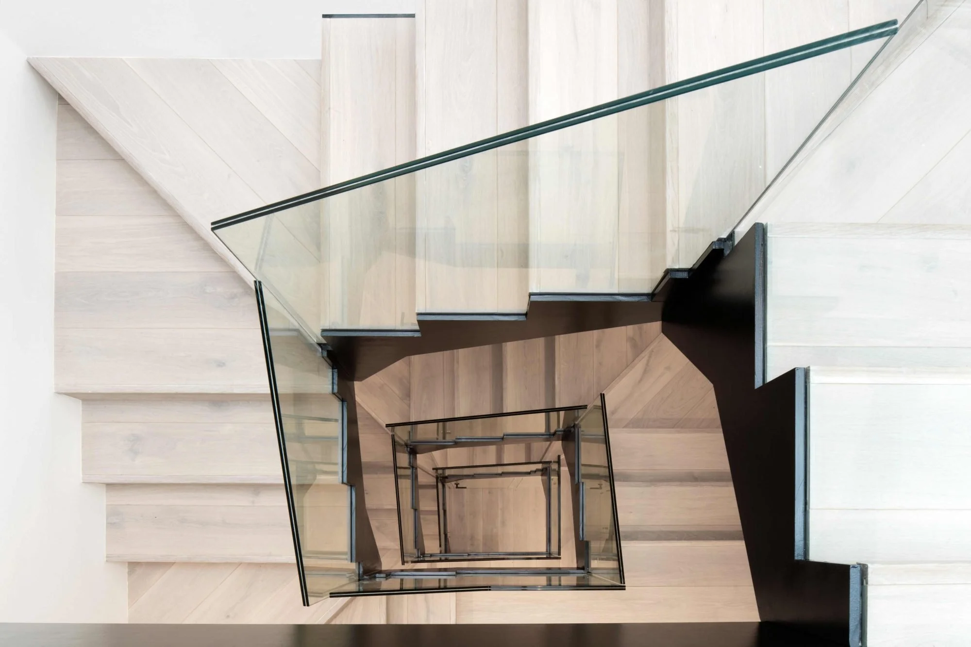 Multiple floors viewed from above, featuring modern staircases with glass railings and wood flooring.
