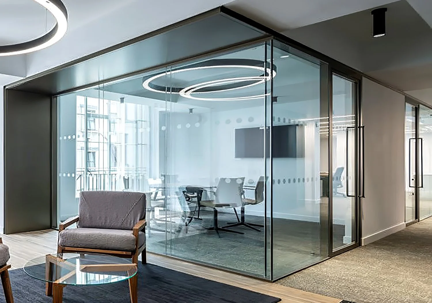 Modern office conference room with glass walls, illuminated ceiling rings, and office furniture