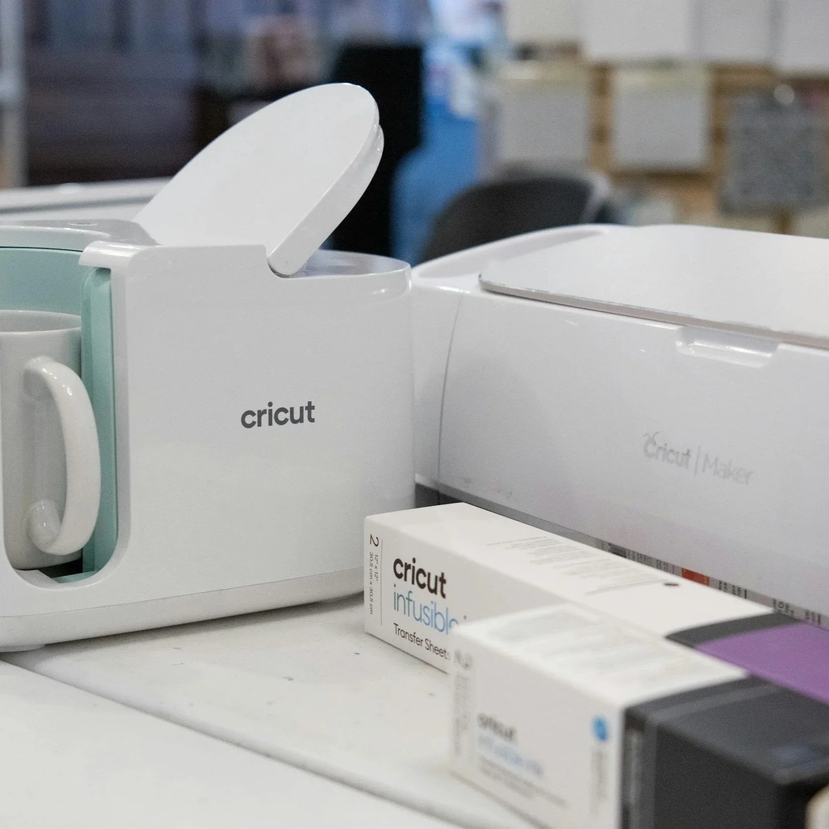 Close-up view of a Cricut brand infusion transfer sheet box on a retail shelf, with a Cricut mug in the background.